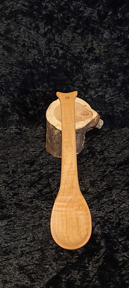 Curly maple wood spoon resting on a log cross-section