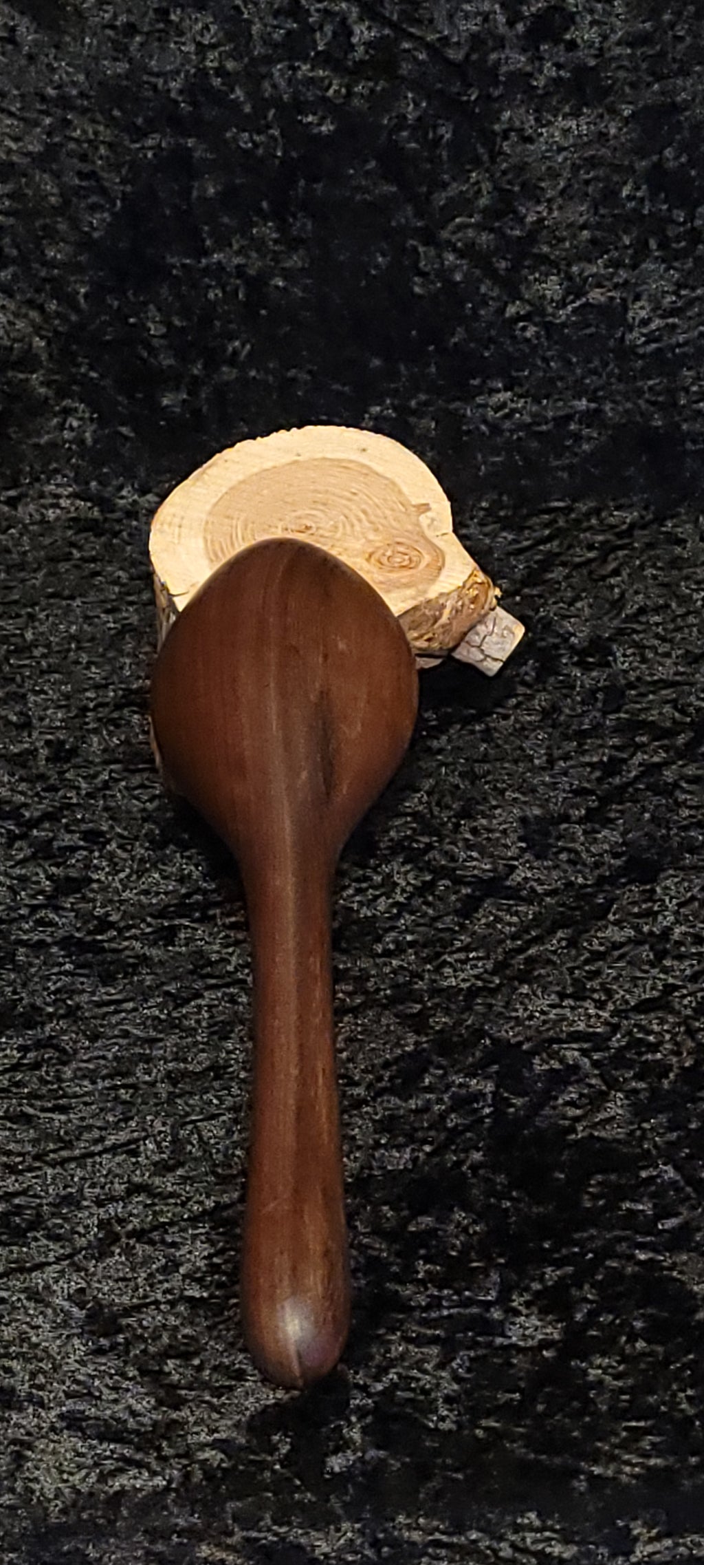 Walnut wood spoon side view on log