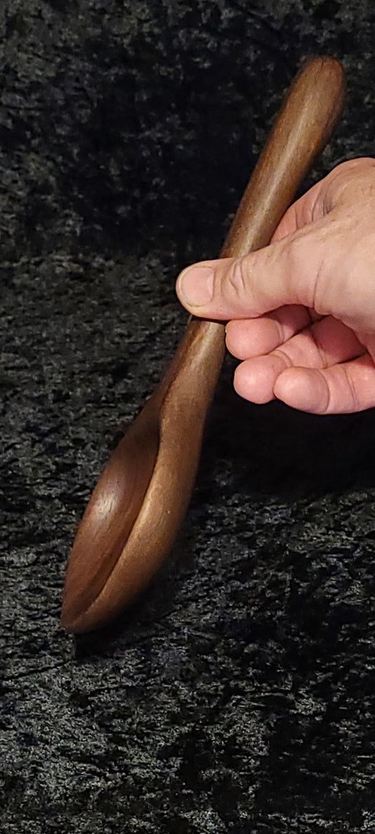 Walnut wood spoon top view resting on log