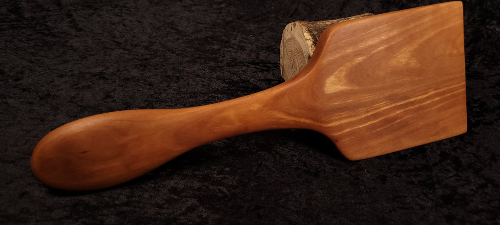 Cherry wood spoon held showing size
