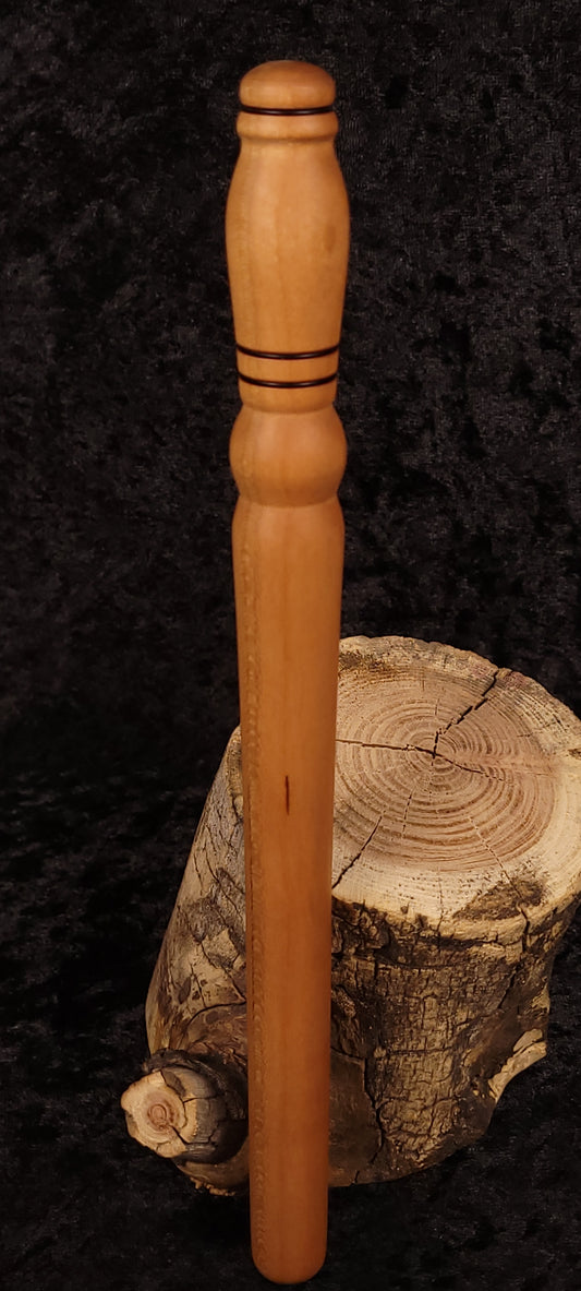 Hand-turned cherry wood rolling pin leaning on log stump - side view 1