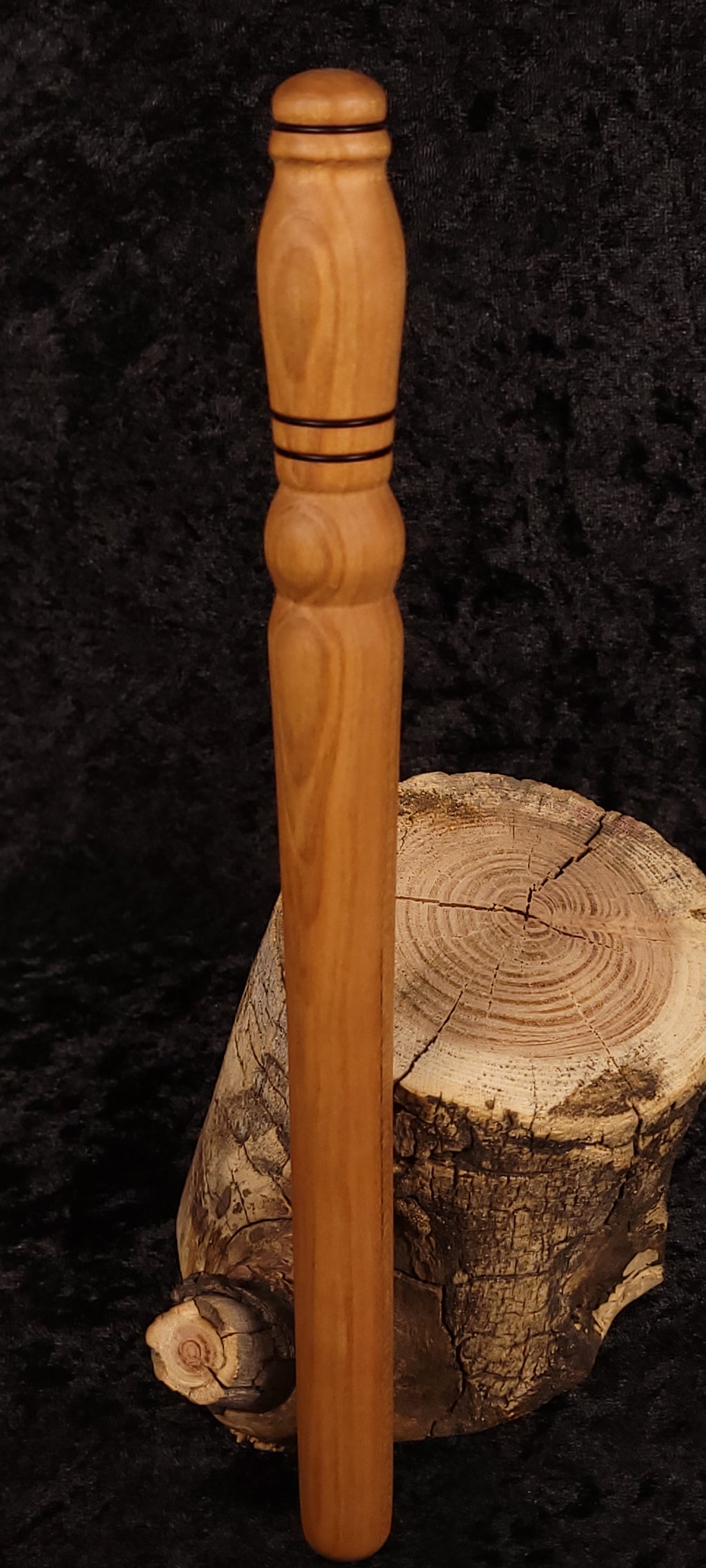 Hand-turned cherry wood rolling pin leaning on log stump - side view 2