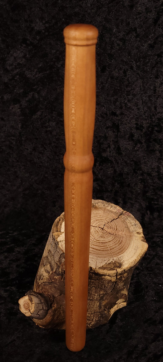 Hand-turned cherry wood spurtle standing upright on log stump - view 1