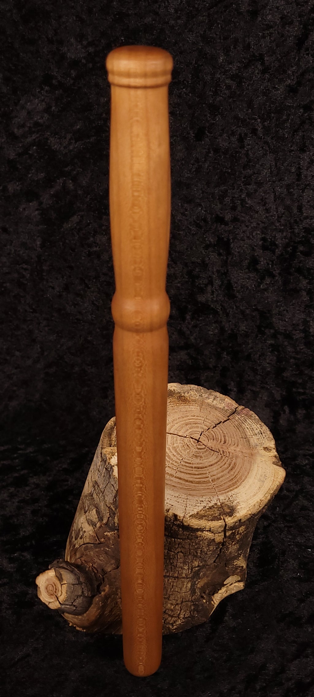 Hand-turned cherry wood spurtle standing upright on log stump - view 2
