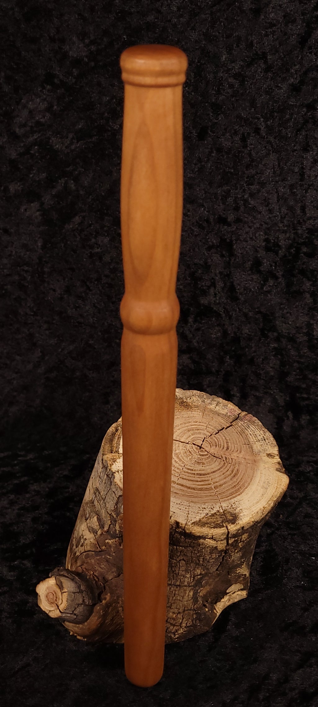Hand-turned cherry wood spurtle standing upright on log stump - view 3