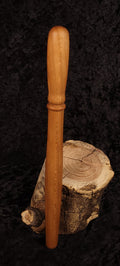 Cherry wood spurtle leaning on log cross-section, front view 1