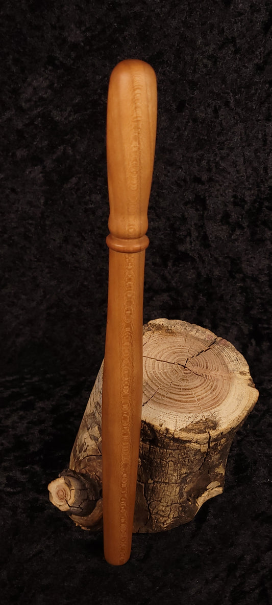 Cherry wood spurtle leaning on log cross-section, front view 1