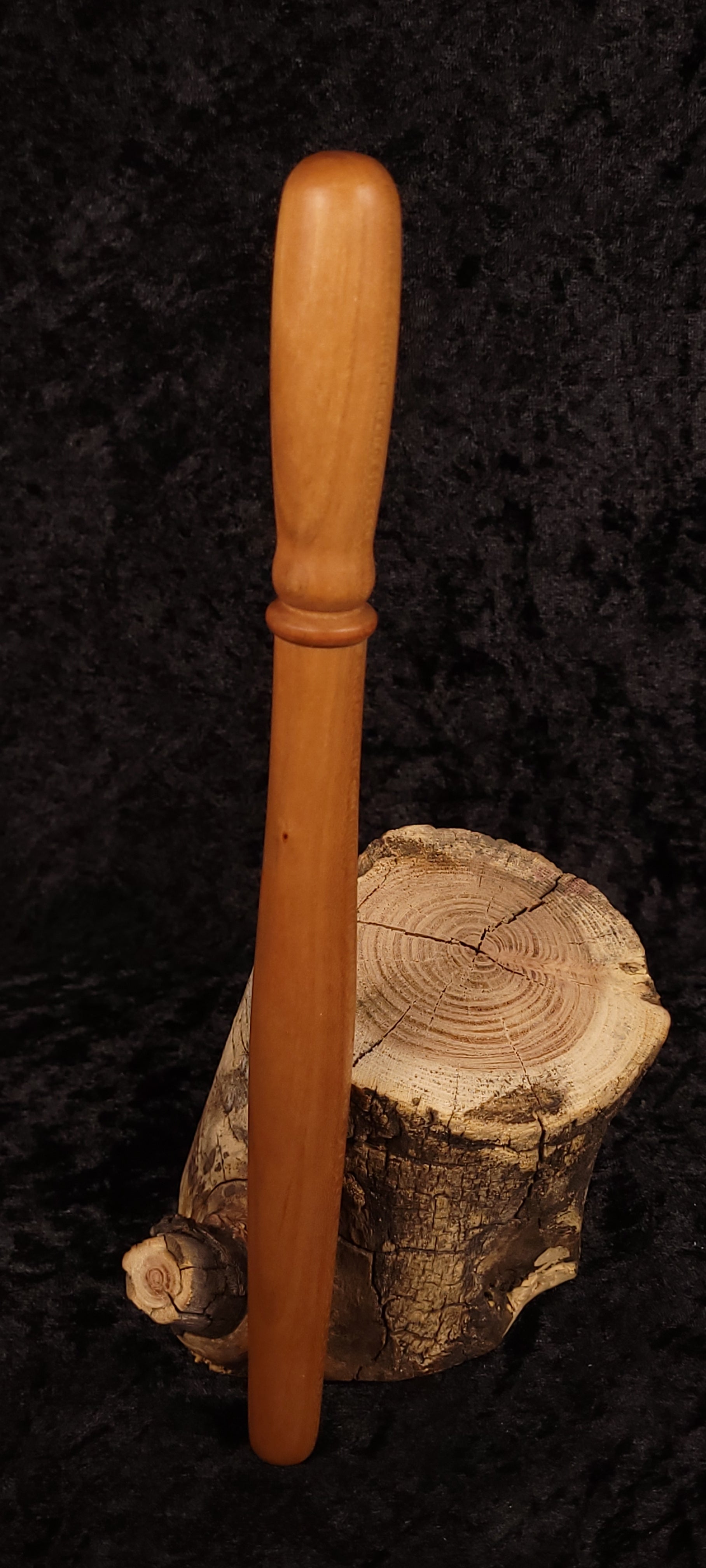Cherry wood spurtle leaning on log cross-section, front view 2