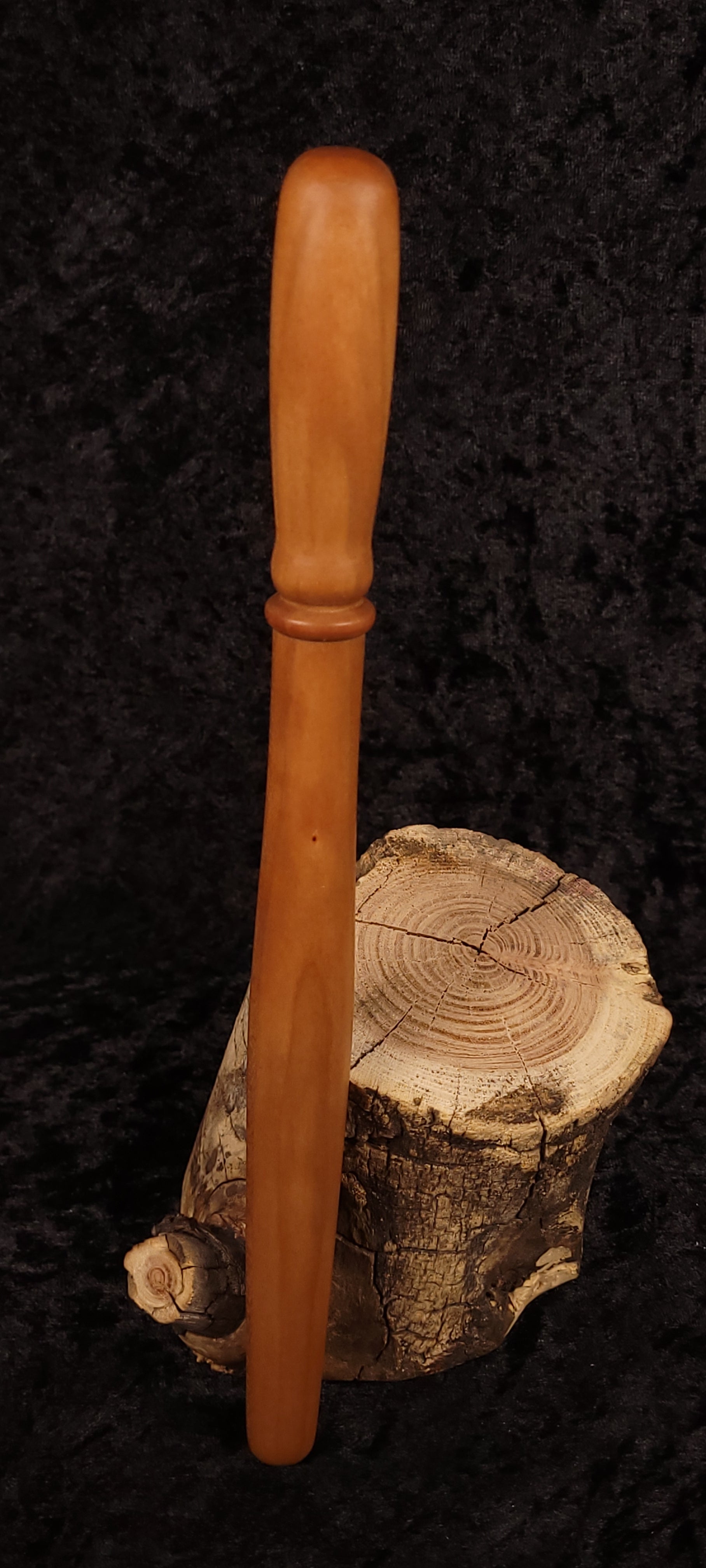 Cherry wood spurtle leaning on log cross-section, front view 3