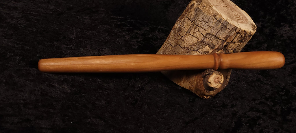 Cherry wood spurtle resting horizontally on log cross-section