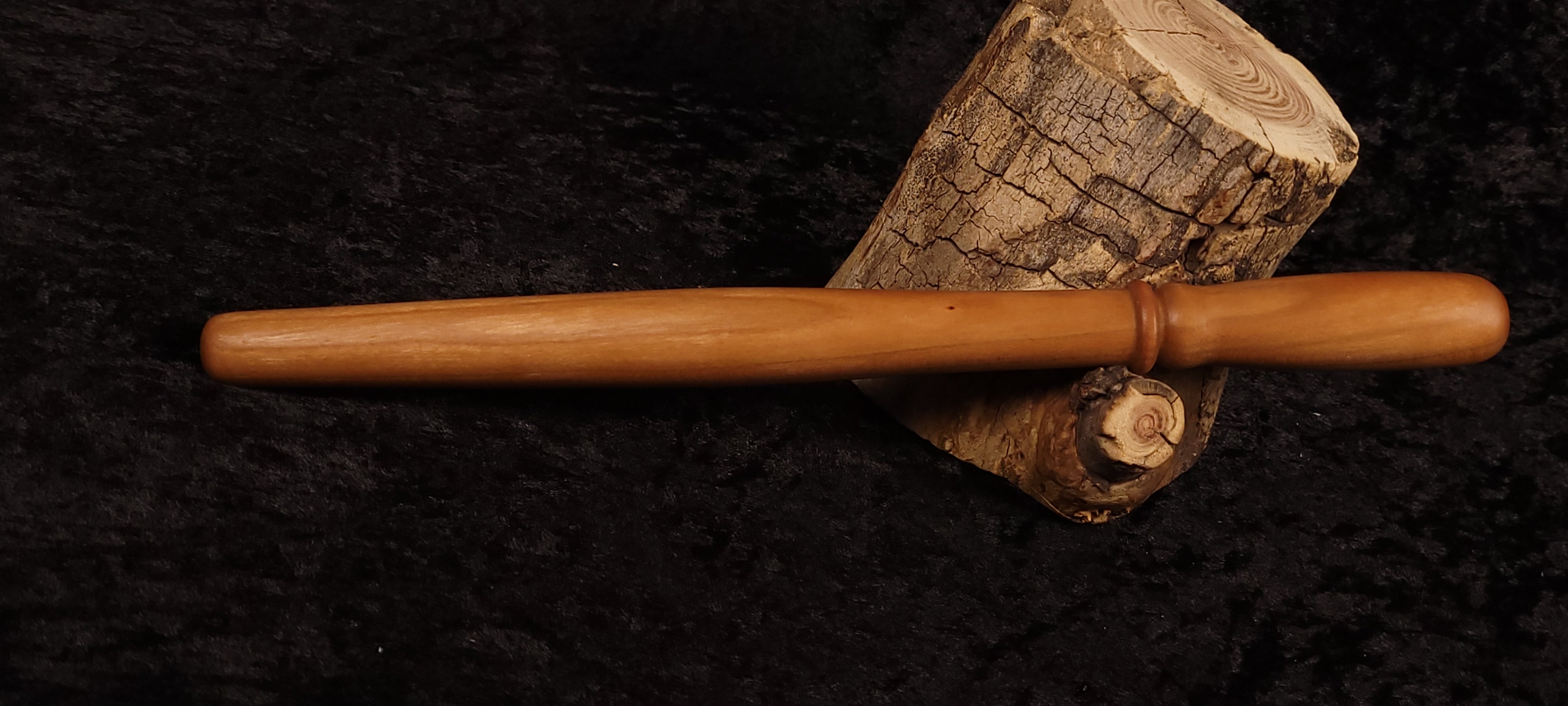 Cherry wood spurtle resting horizontally on log cross-section