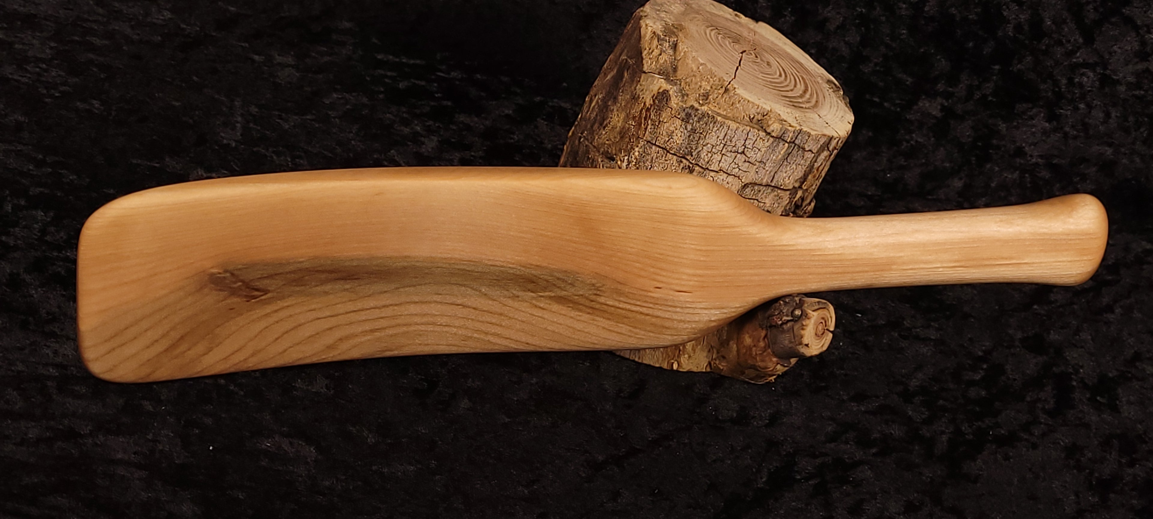 Curly maple spatula back view leaning on log