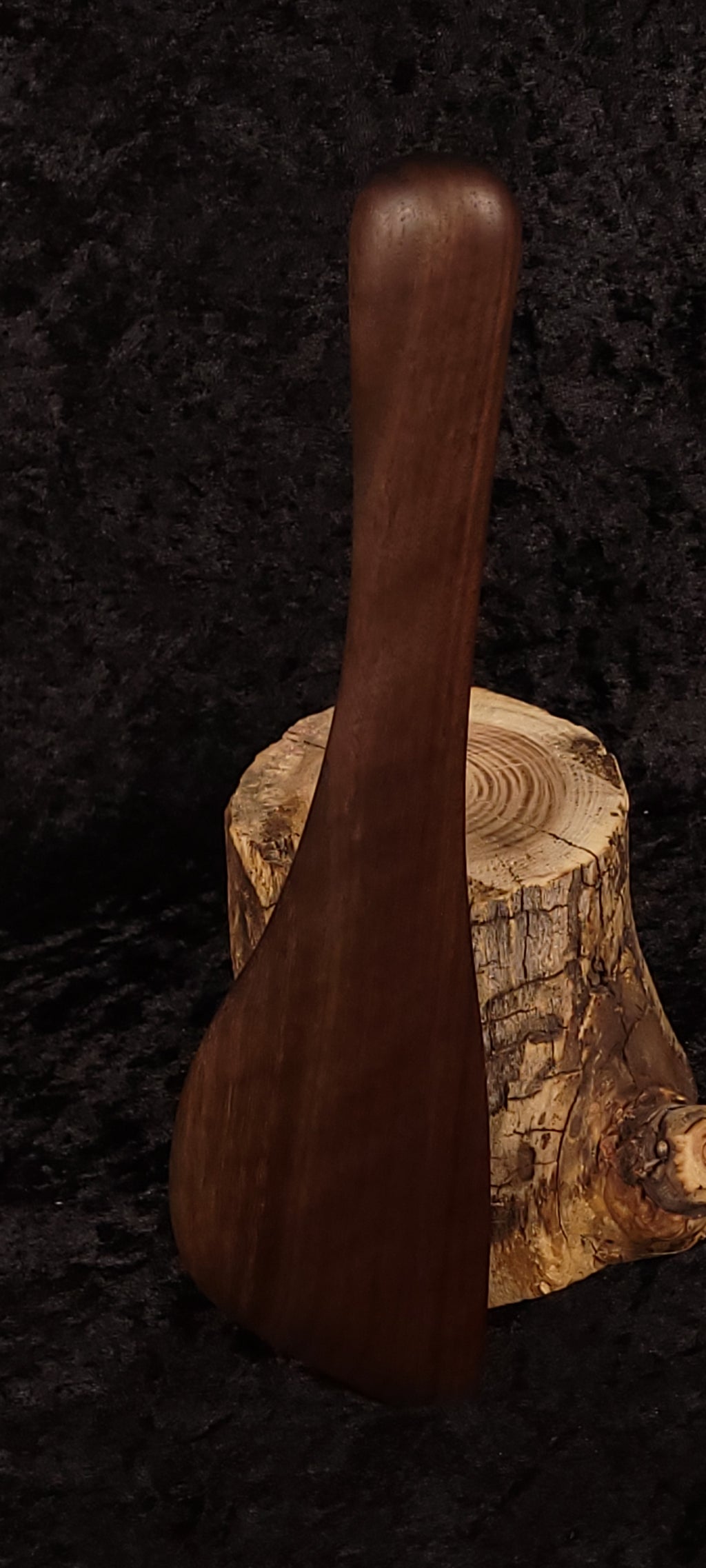 Handcrafted walnut angled spatula back view balanced on log