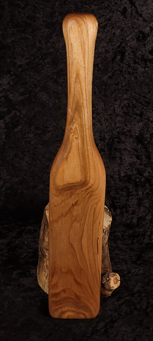 Curly maple spatula front view standing upright on log