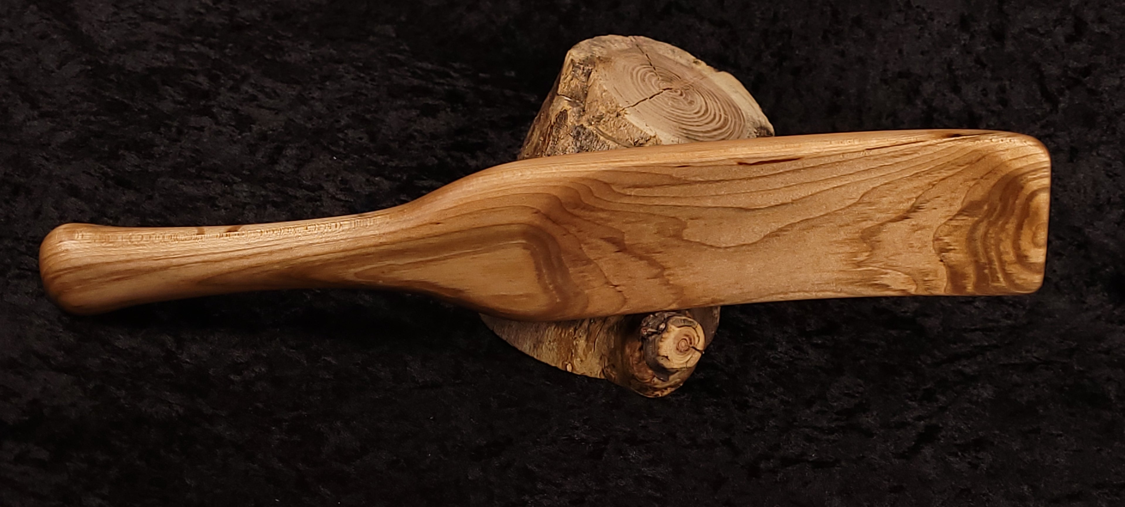 Curly maple spatula side view horizontal on log