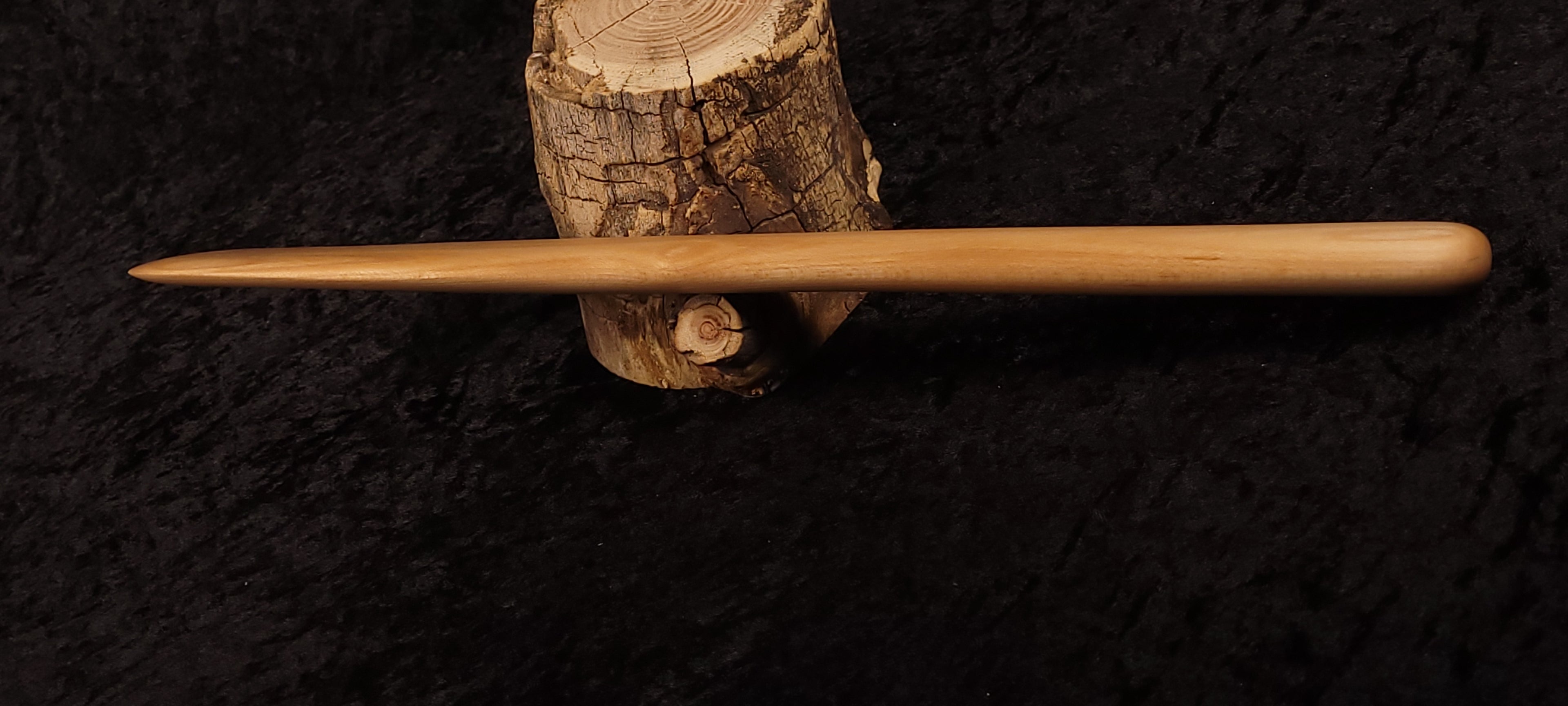 Hand holding maple wood spurtle vertically showing taper
