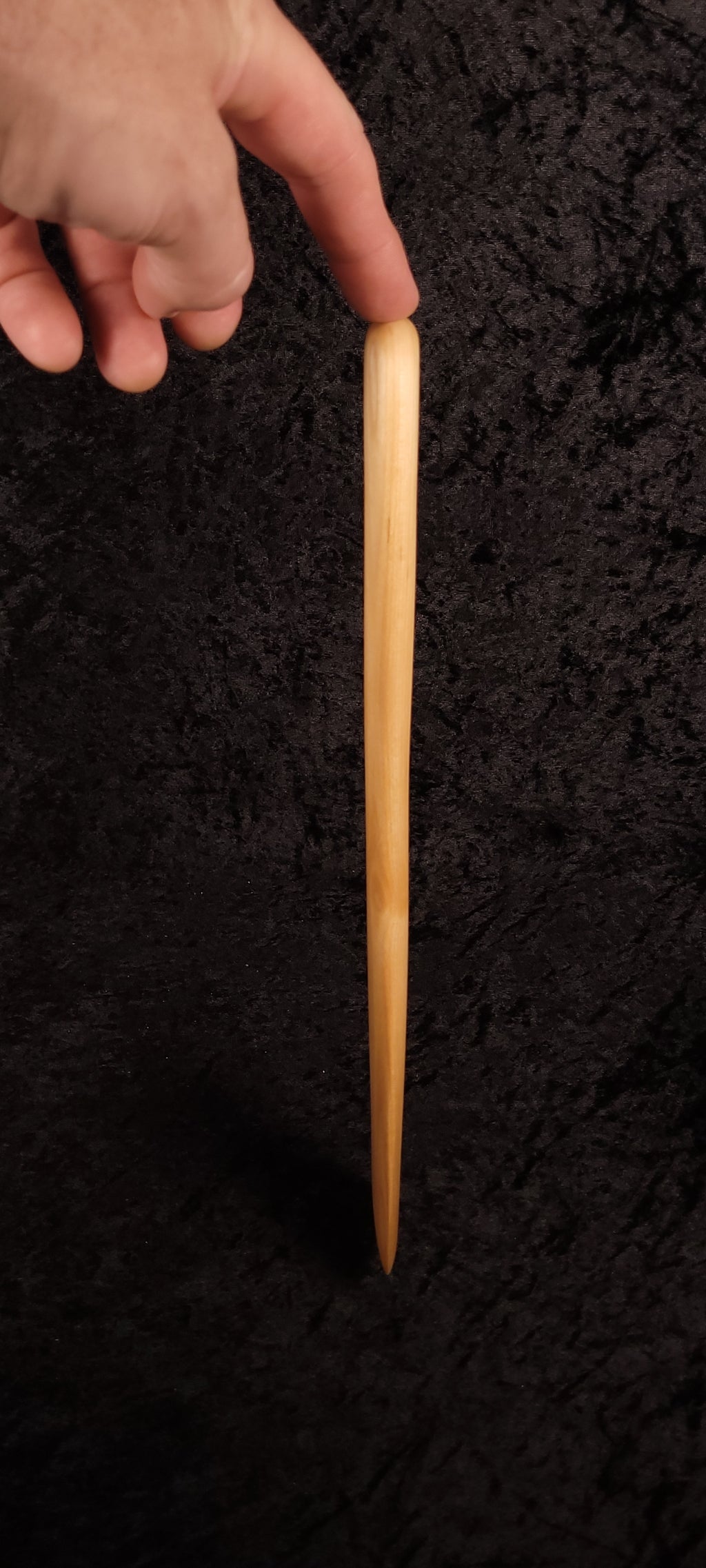 Maple wood spurtle with rounded ends balanced on a log