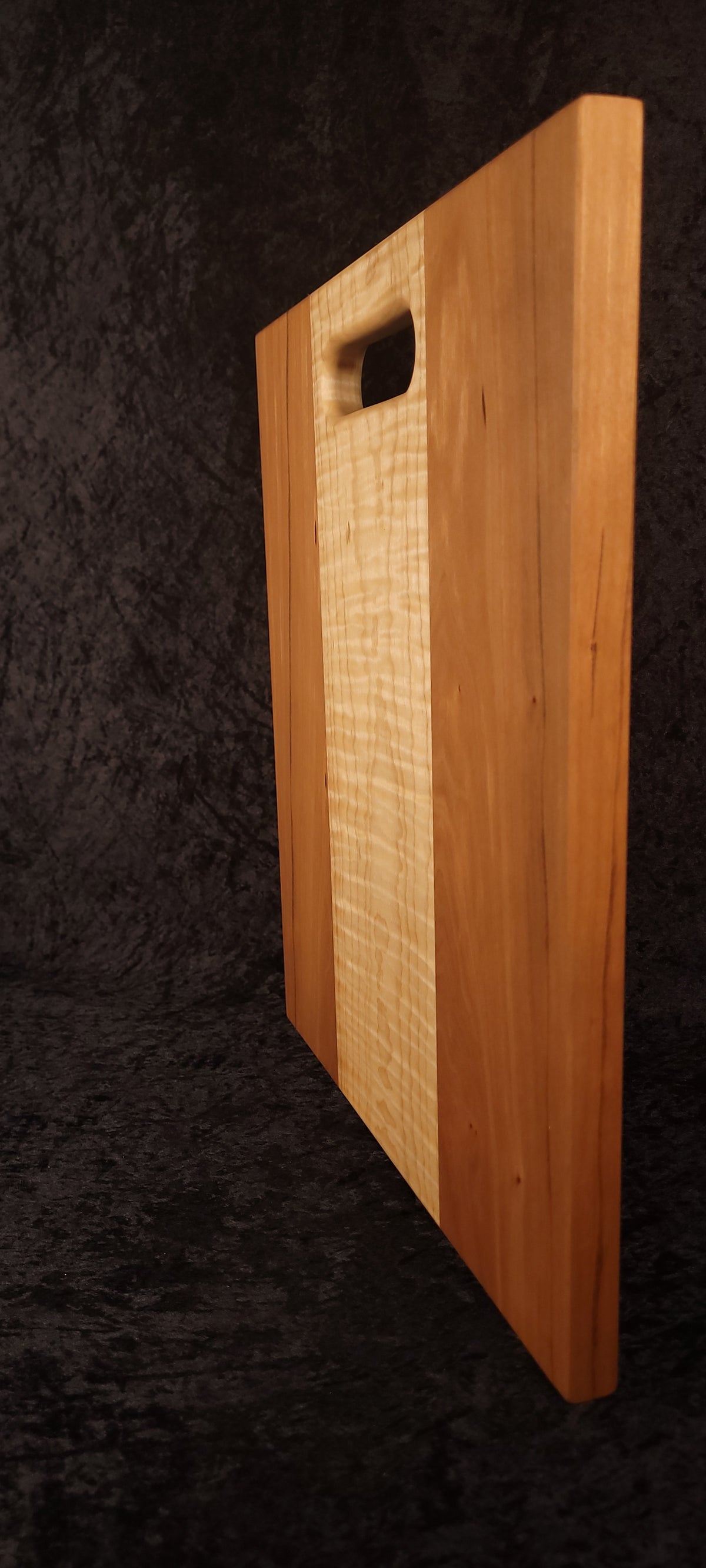 Cutting board standing on edge showing thickness and curly maple stripe