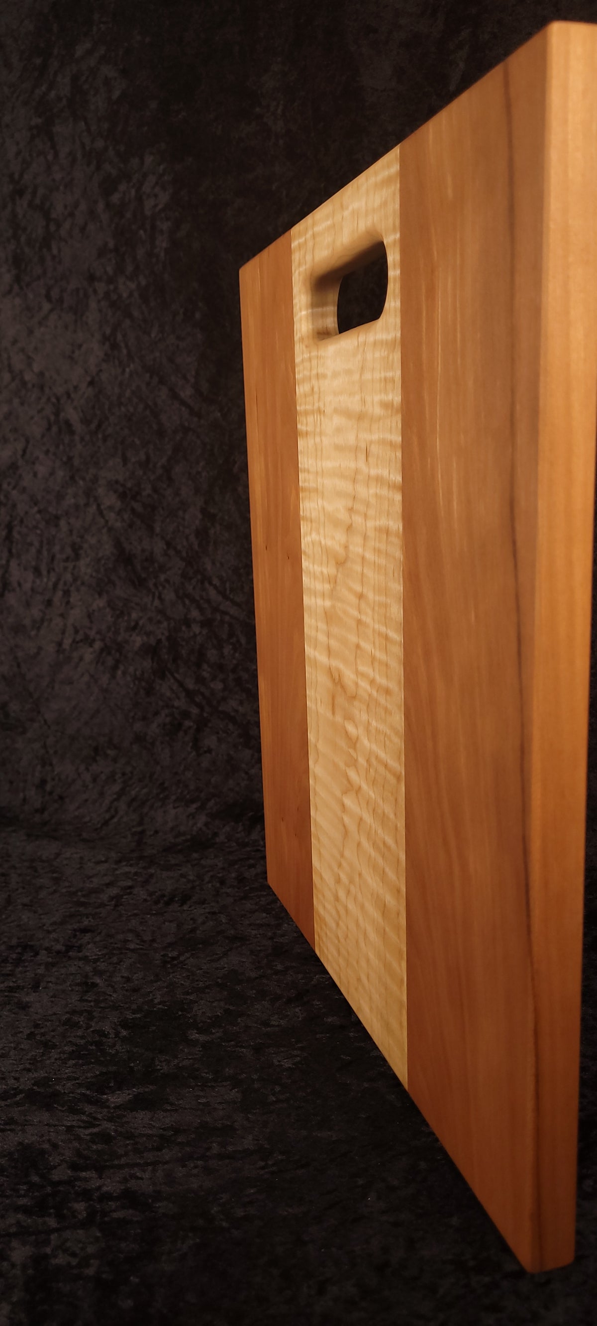 Cutting board standing on opposite edge showing cherry grain and maple center