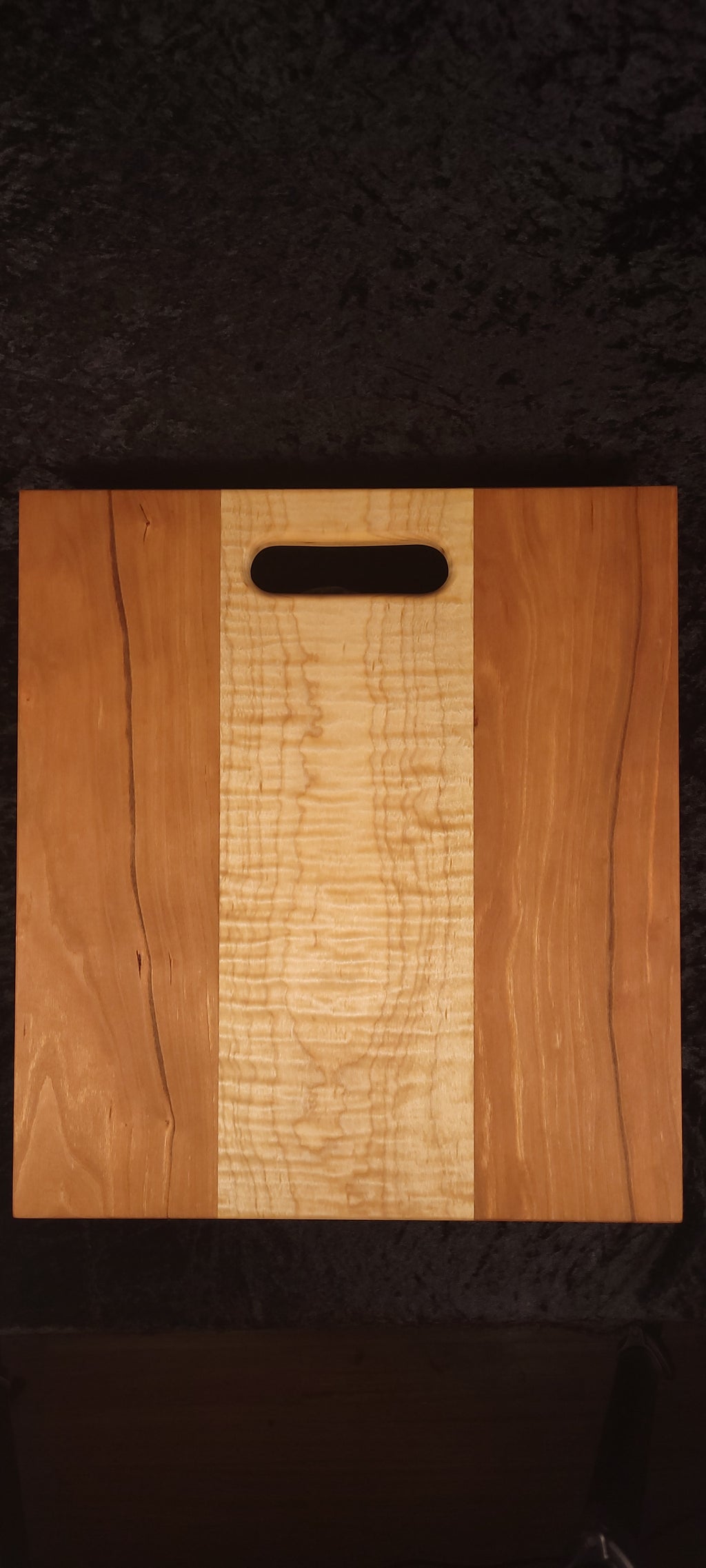 Cherry and curly maple cutting board face, alternate angle showing live-edge cherry detail