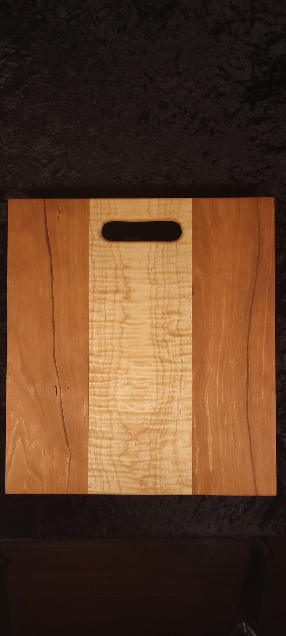Cherry and curly maple cutting board face, alternate angle showing live-edge cherry detail