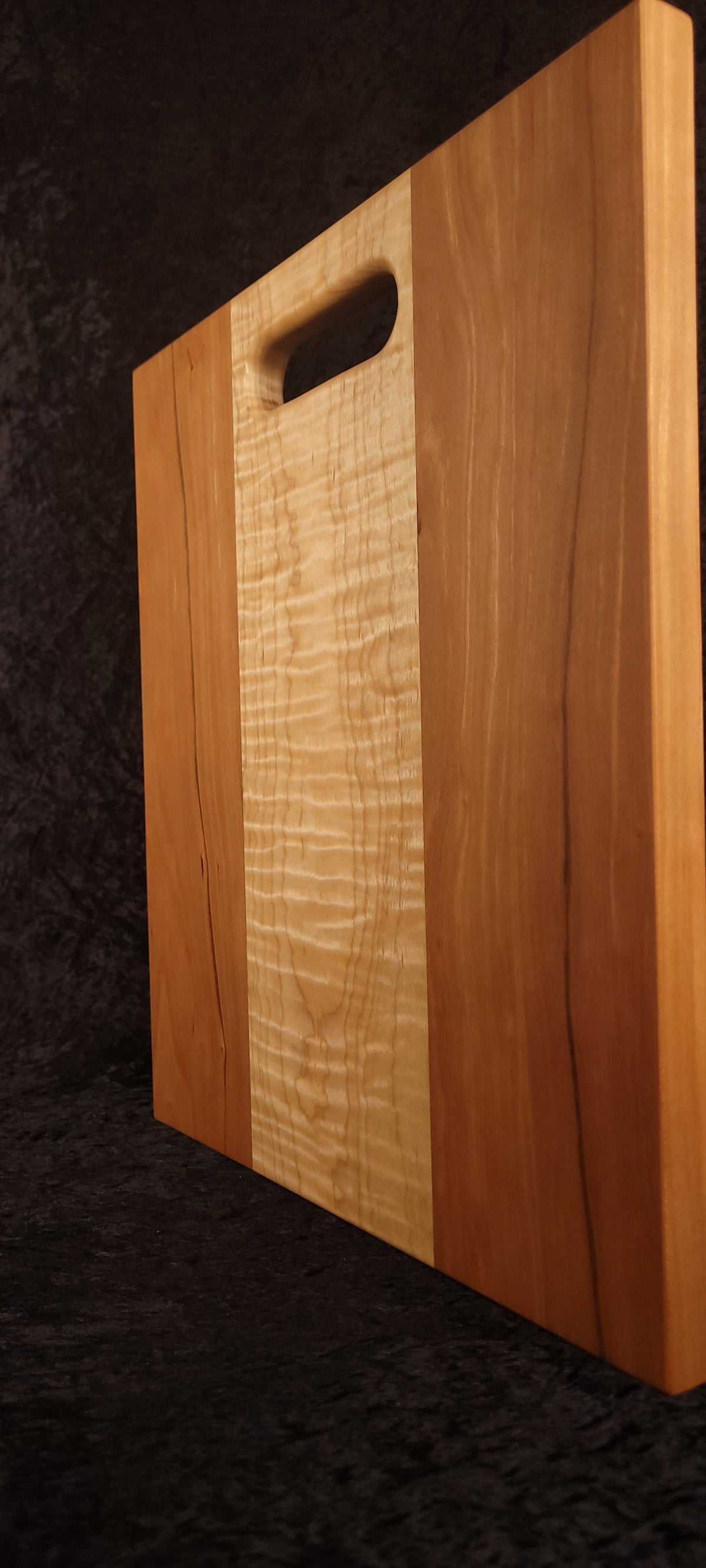 Cutting board standing on edge showing thickness and curly maple stripe