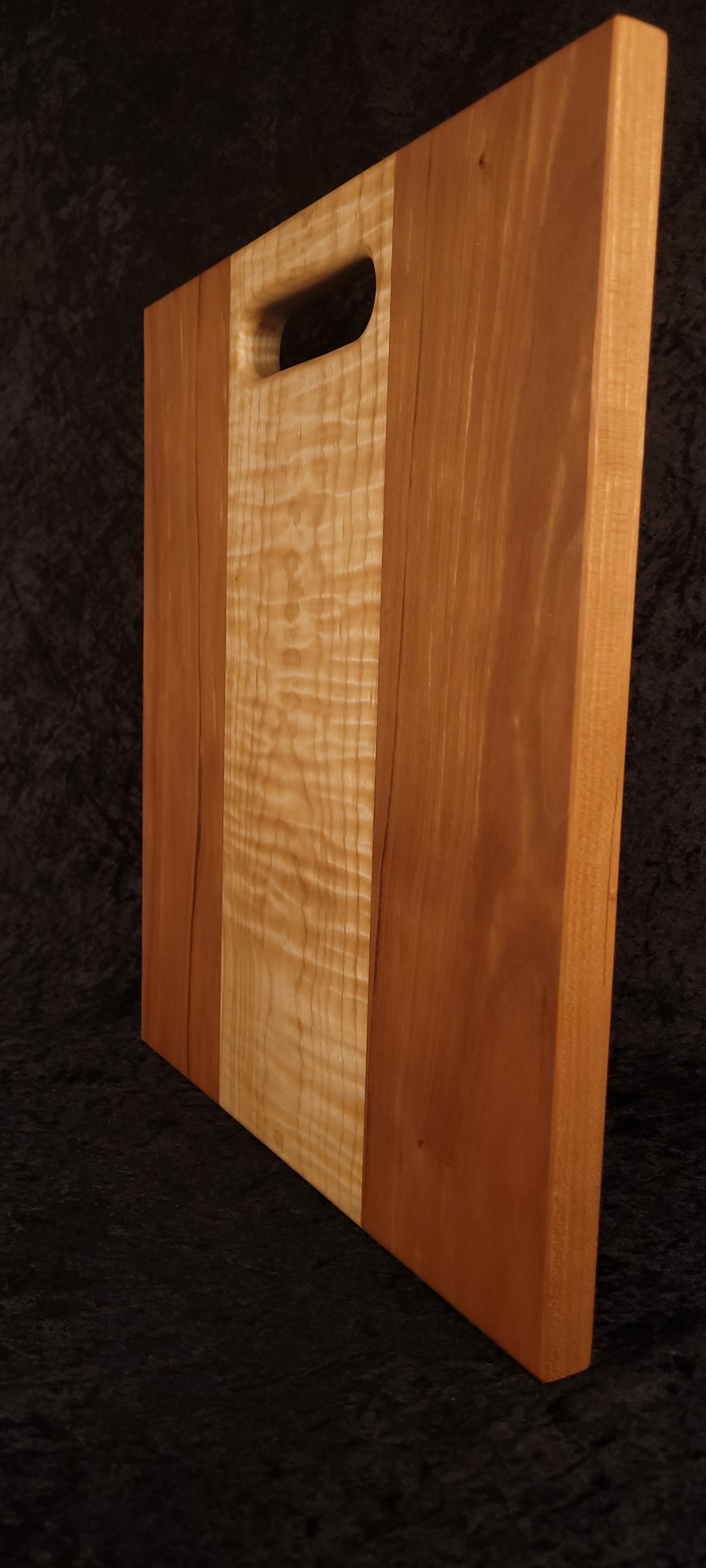 Cutting board standing on opposite edge showing cherry grain and maple center
