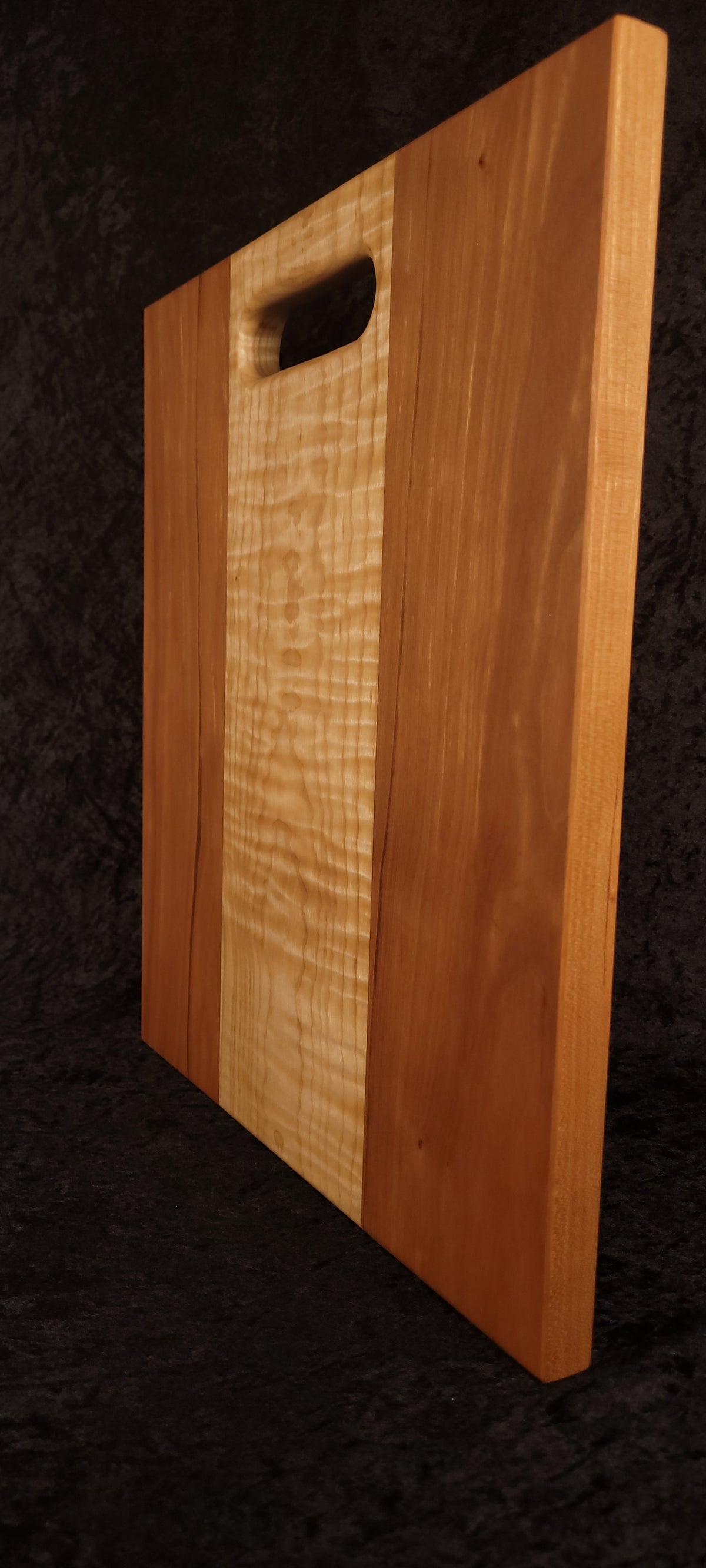 Cutting board standing on opposite edge showing cherry grain and maple center
