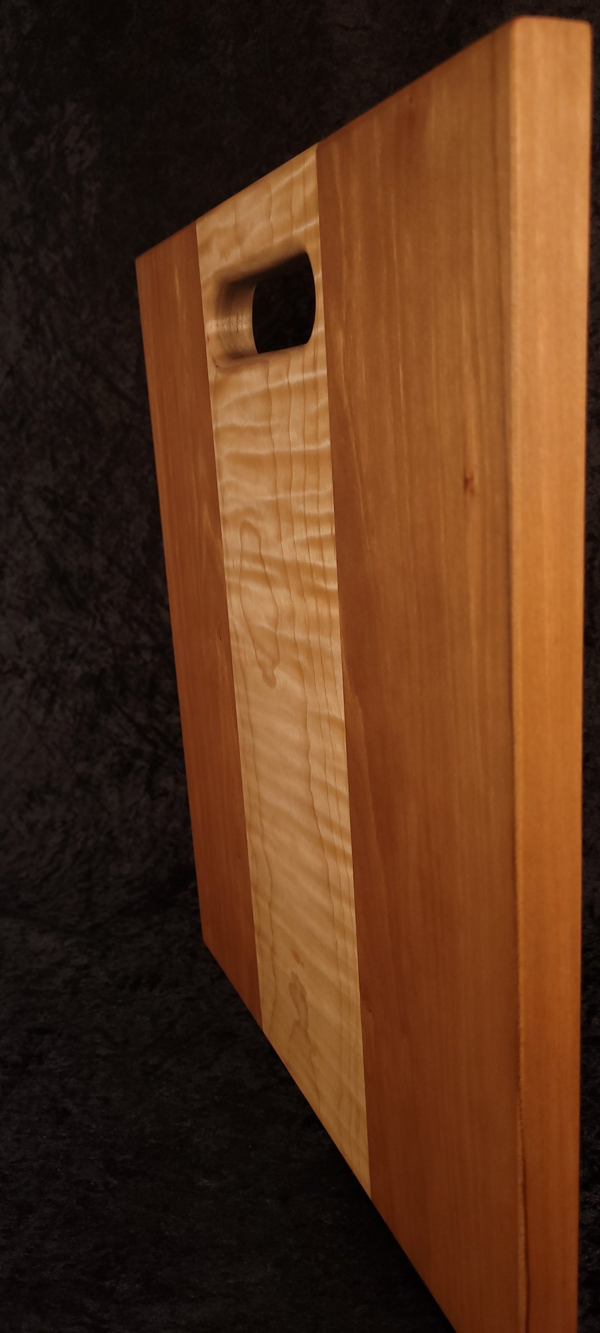 Cutting board standing on opposite edge showing cherry and curly maple detail