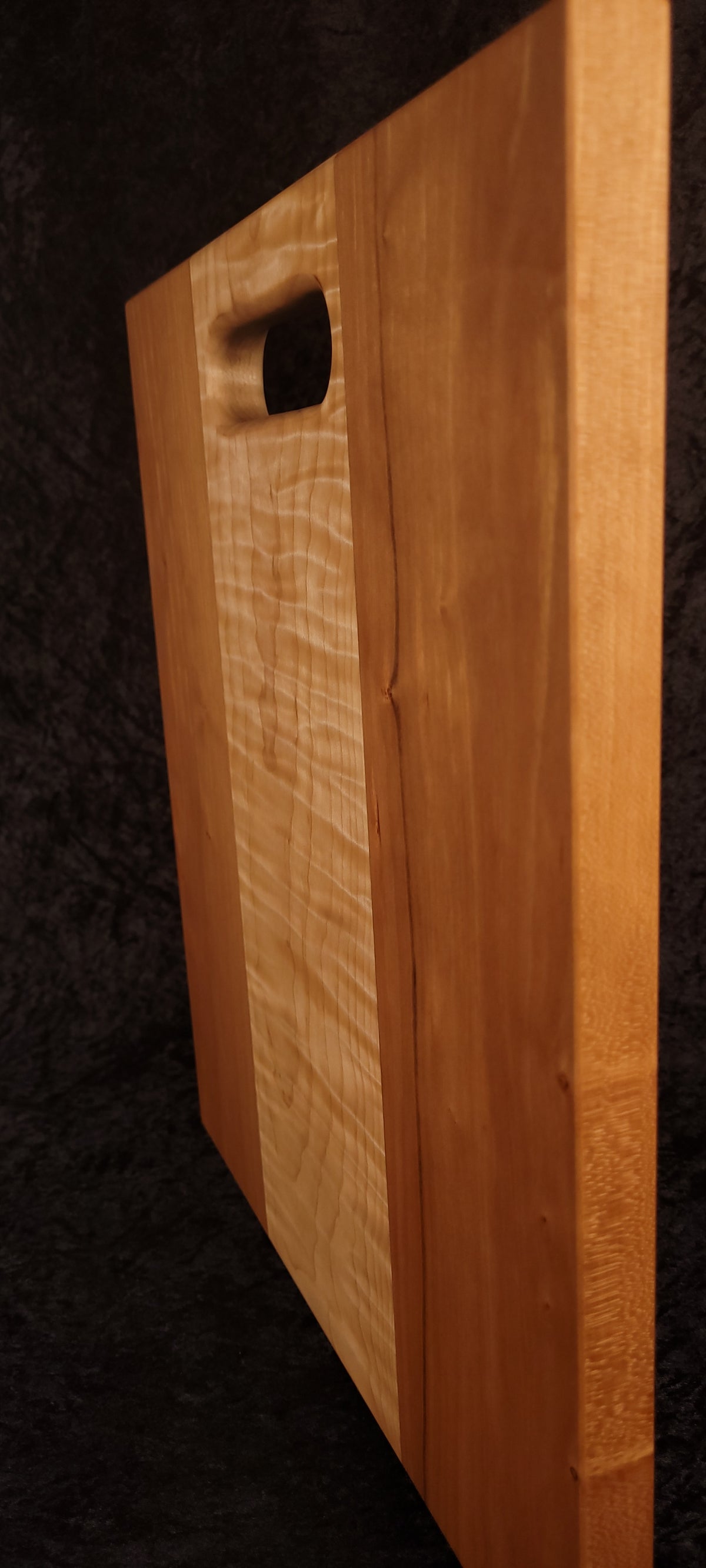 Cutting board standing on edge showing thickness and curly maple stripe