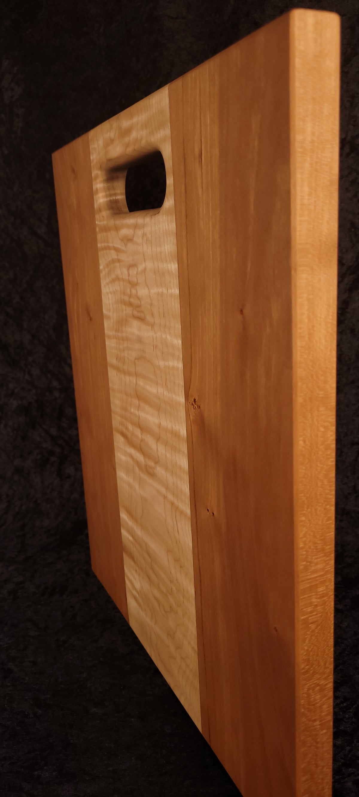Cutting board standing on opposite edge showing cherry grain and maple center