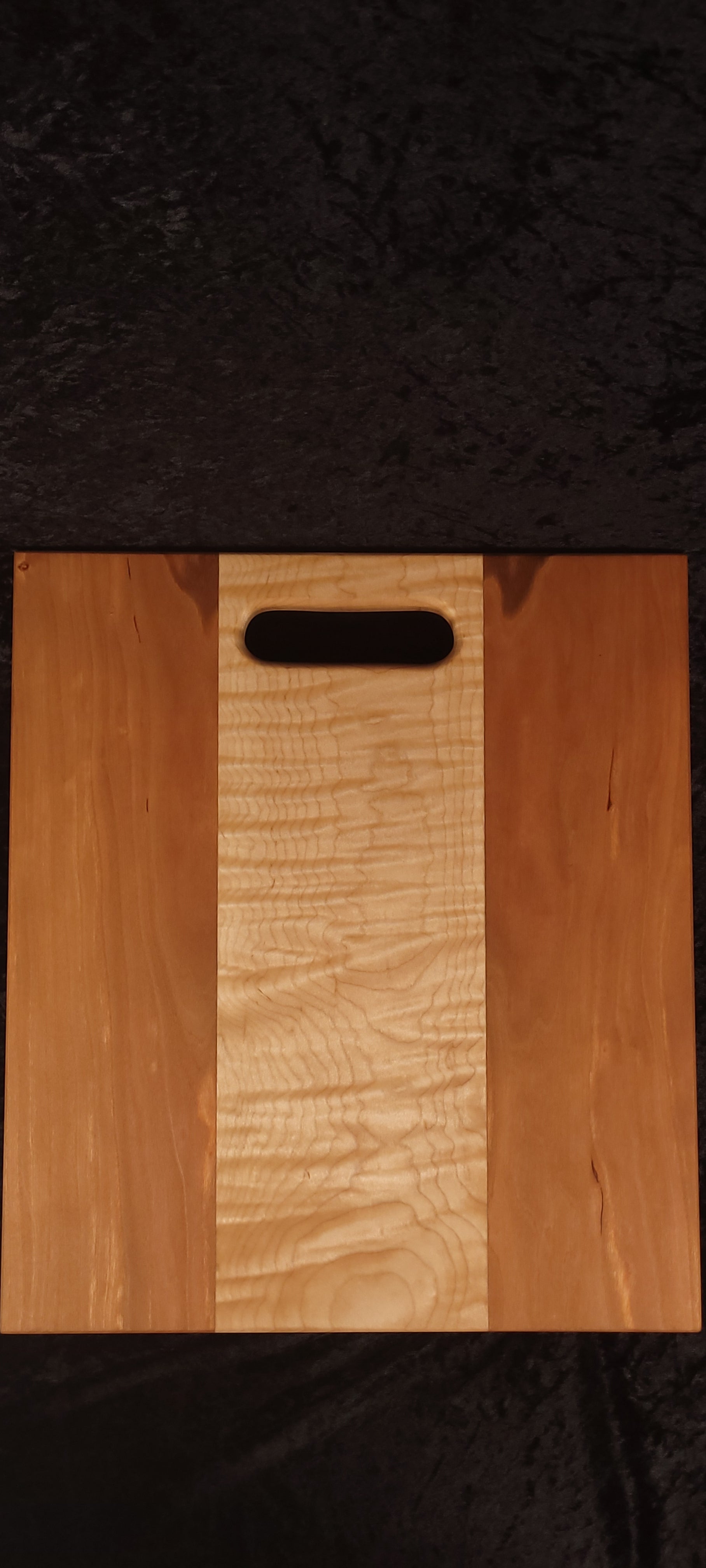 Cherry and curly maple cutting board face, alternate angle showing cathedral grain pattern