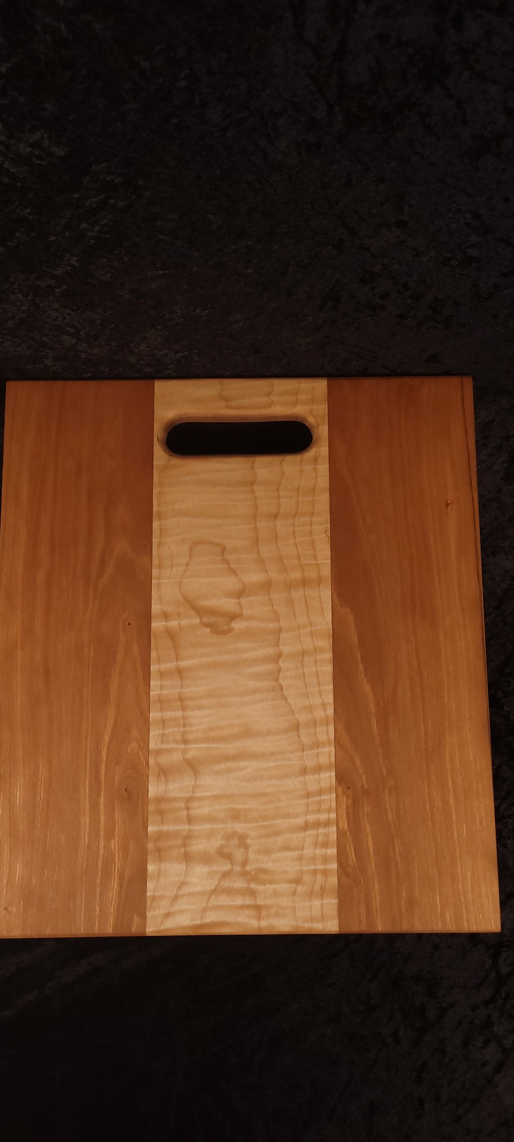 Cherry and curly maple cutting board face showing warm cherry panels and curly maple center