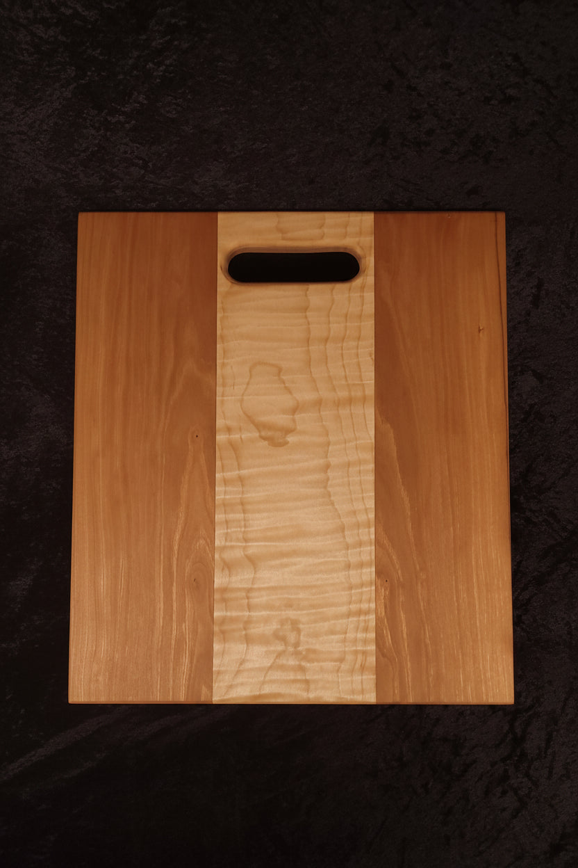 Cherry and curly maple cutting board face showing warm cherry panels and curly maple center
