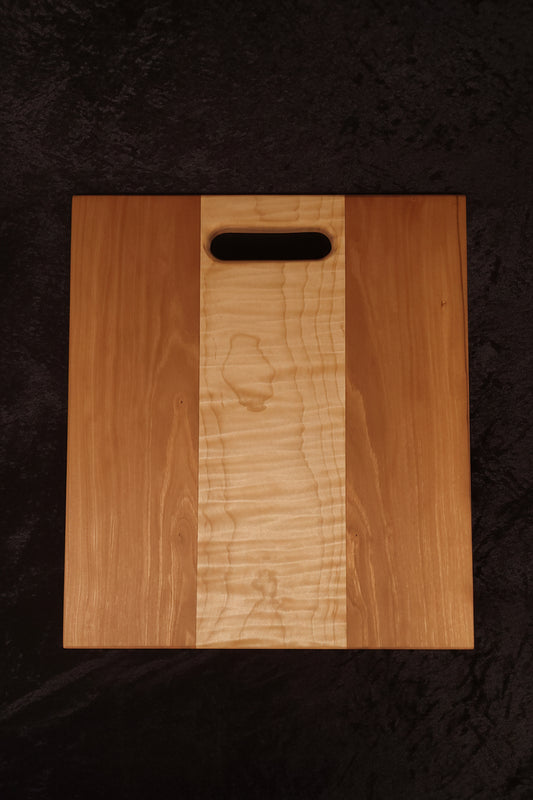 Cherry and curly maple cutting board face showing warm cherry panels and curly maple center