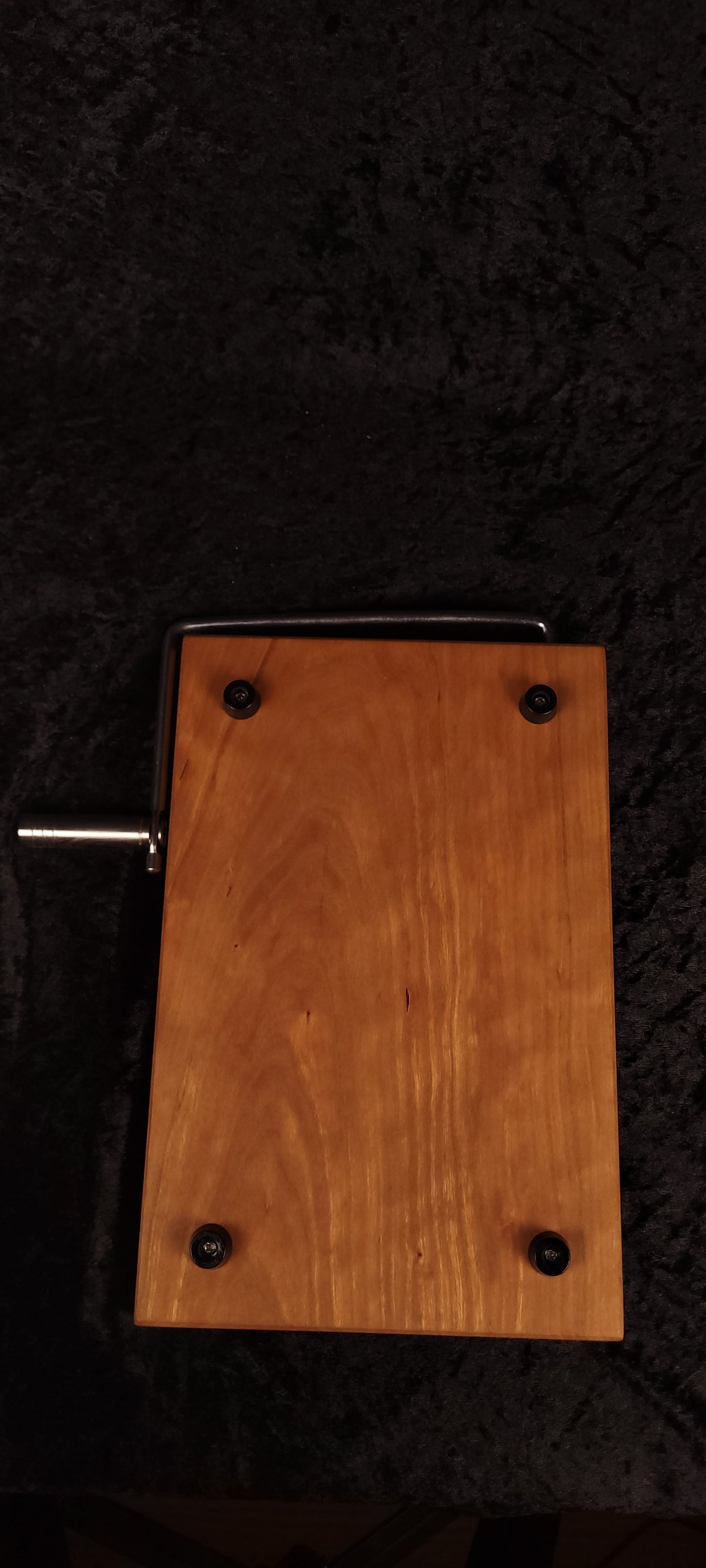 Cherry cheese board with stainless wire cutter raised, propped on wood slice with cheese