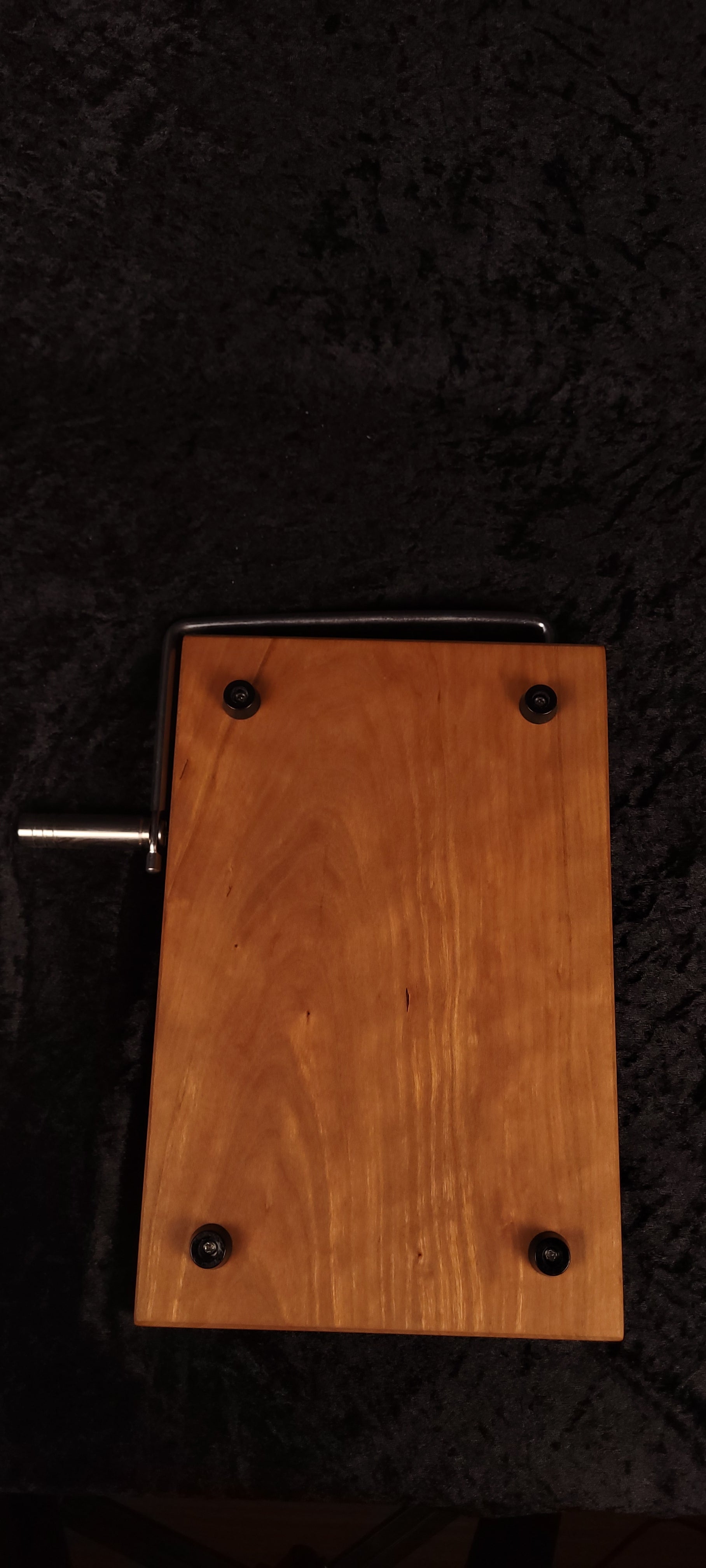 Cherry cheese board with stainless wire cutter raised, propped on wood slice with cheese