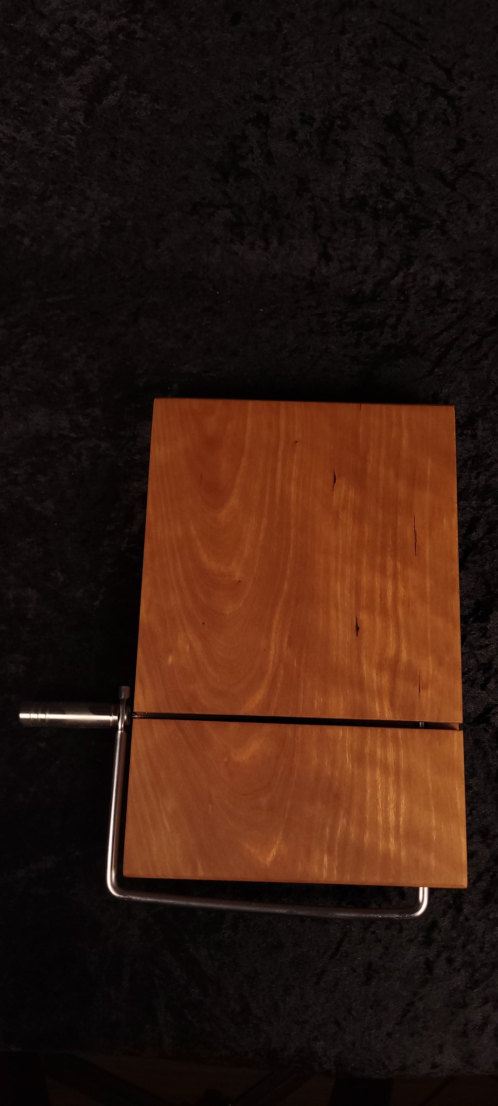 Cherry cheese board angled on wood slice showing stainless wire cutter