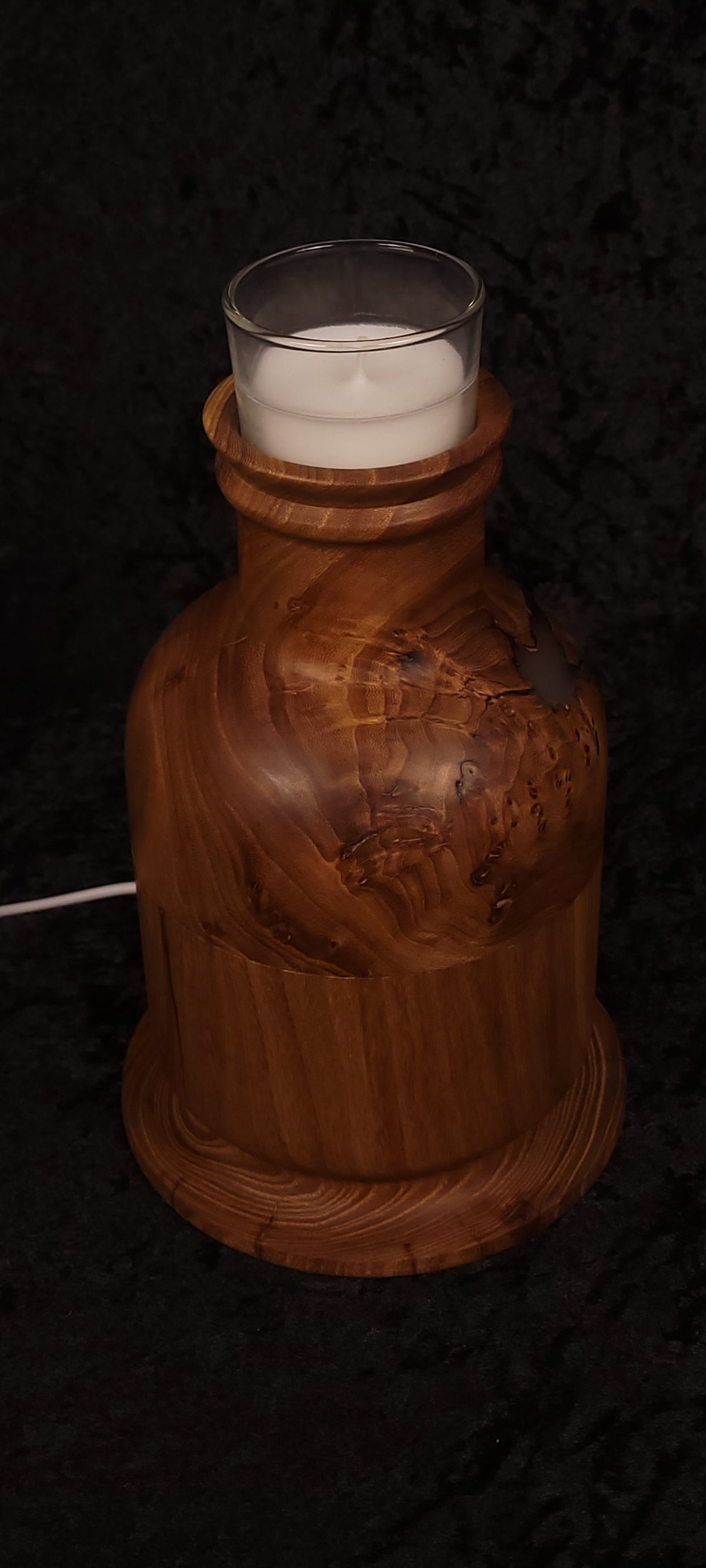 Hand holding elm candle lamp showing scale and warm glow through void