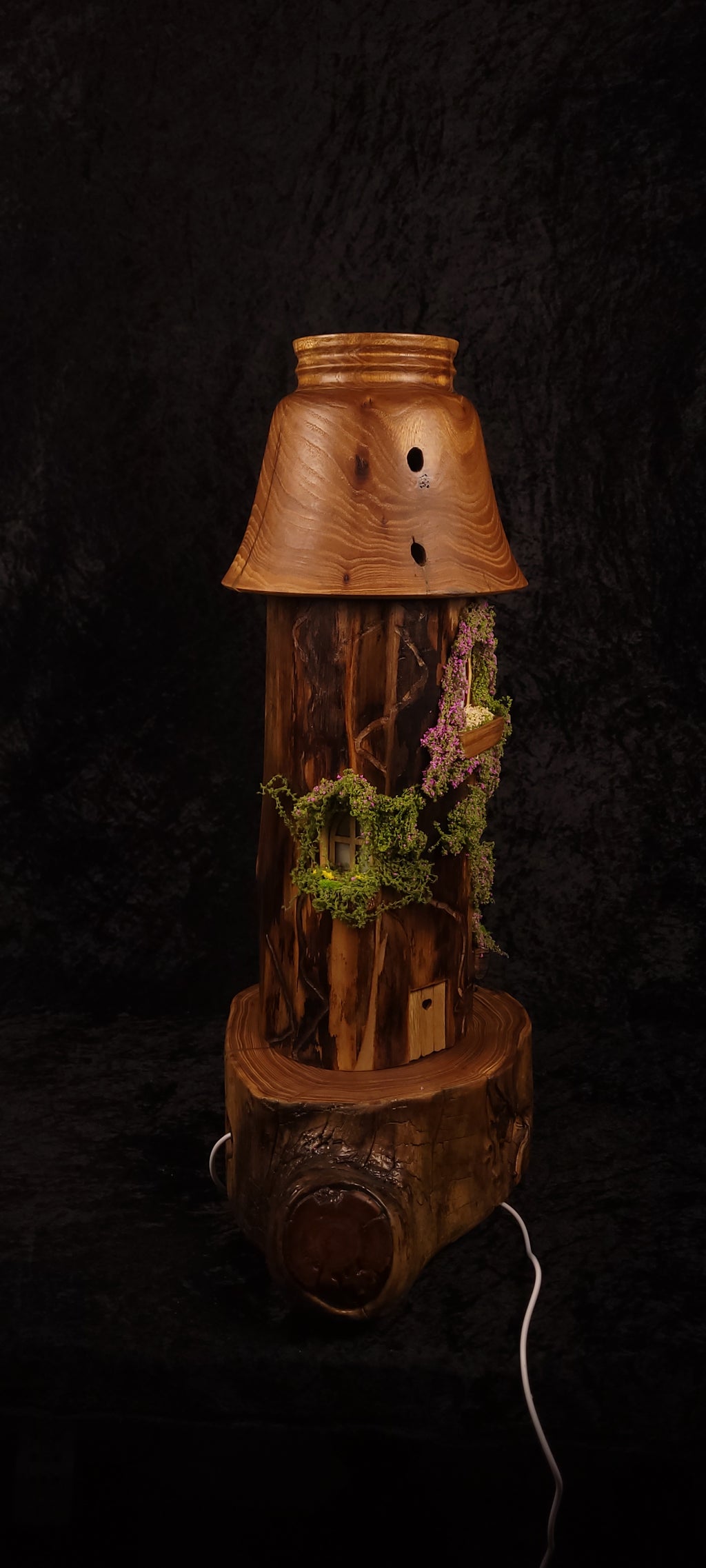 Fairy tower lamp lit with pink glow, side view showing moss and window detail