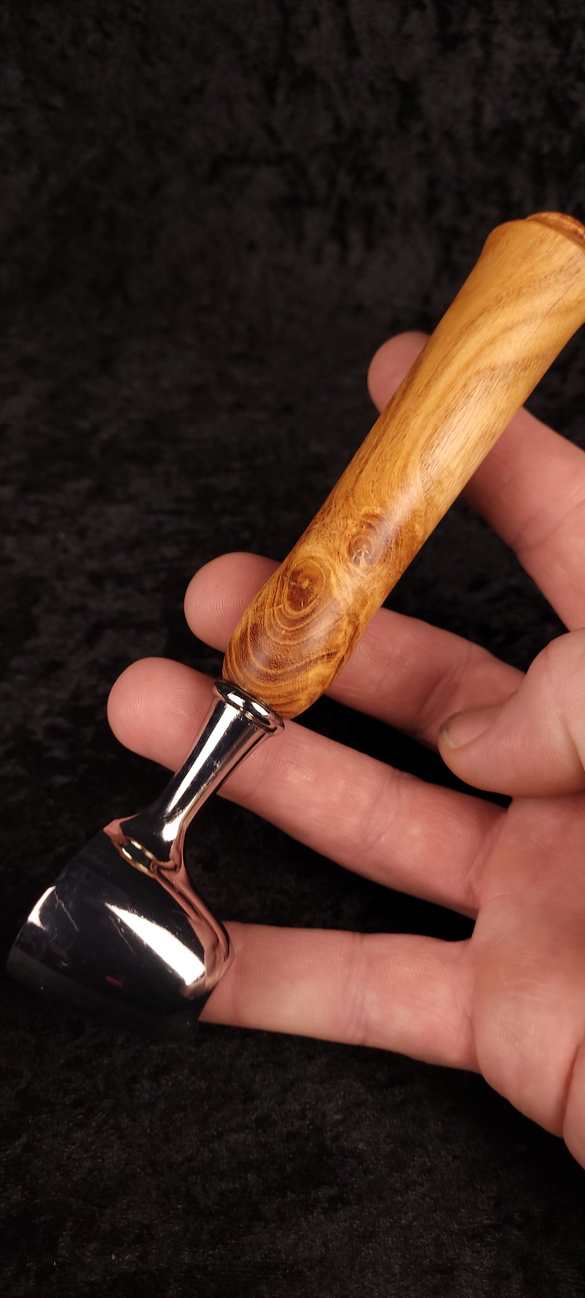 Locust wood coffee scoop held in hand showing scale and chrome finish