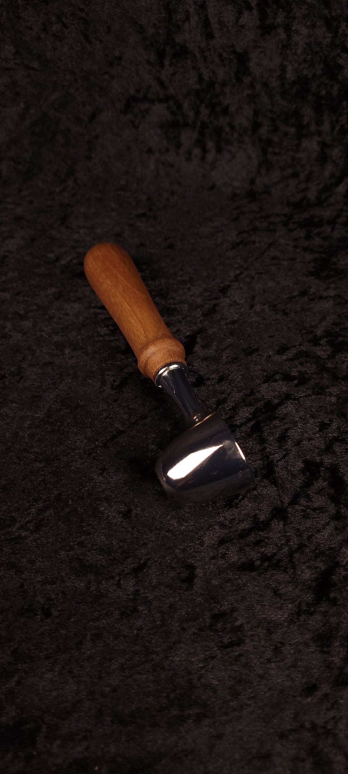 Walnut coffee scoop angled view on black background showing chrome dome and warm brown handle