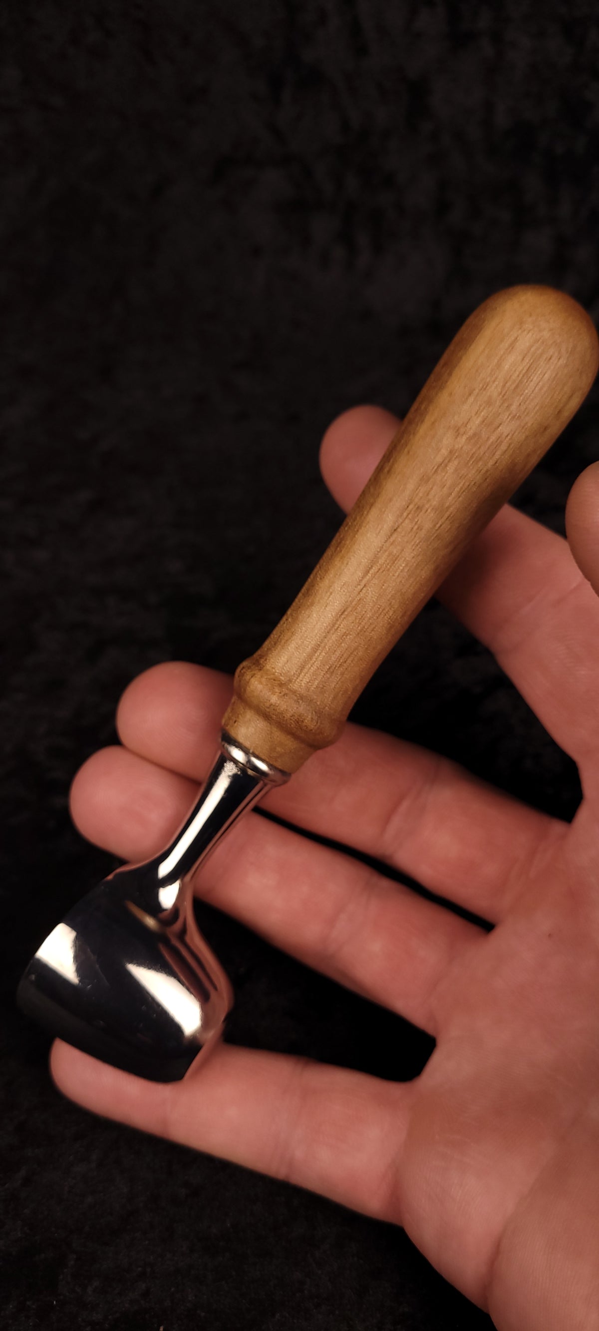 Walnut coffee scoop held in hand showing scale, chrome finish and warm walnut handle