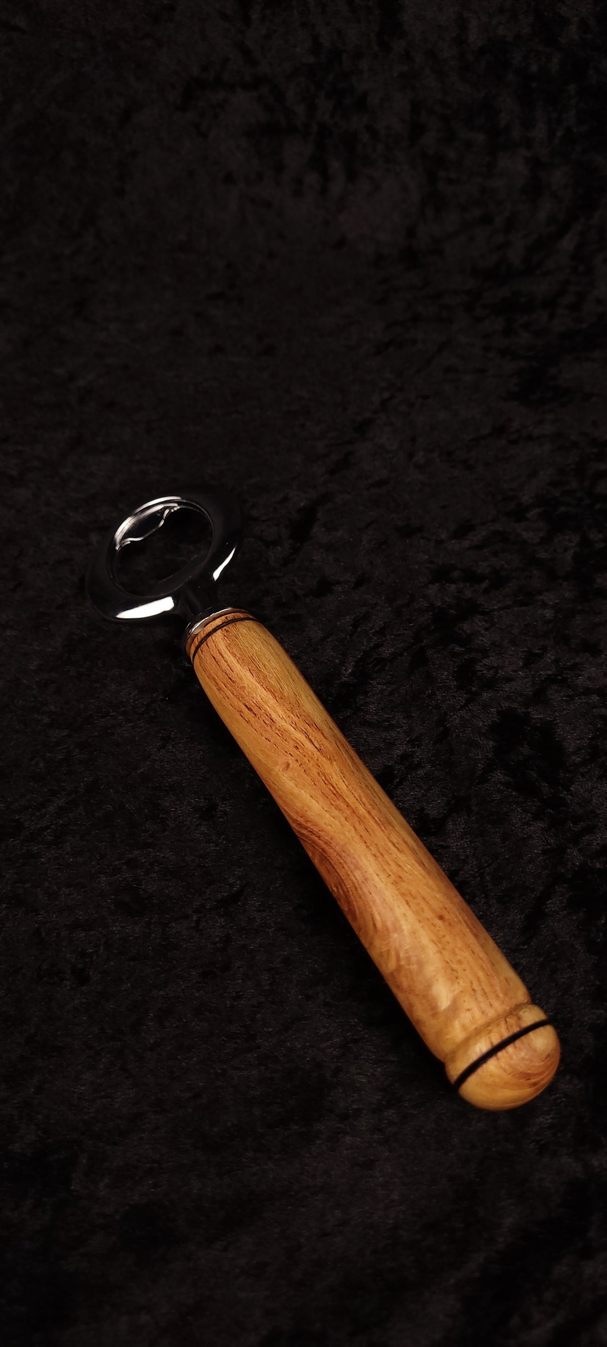Locust wood bottle opener held in hand, front view