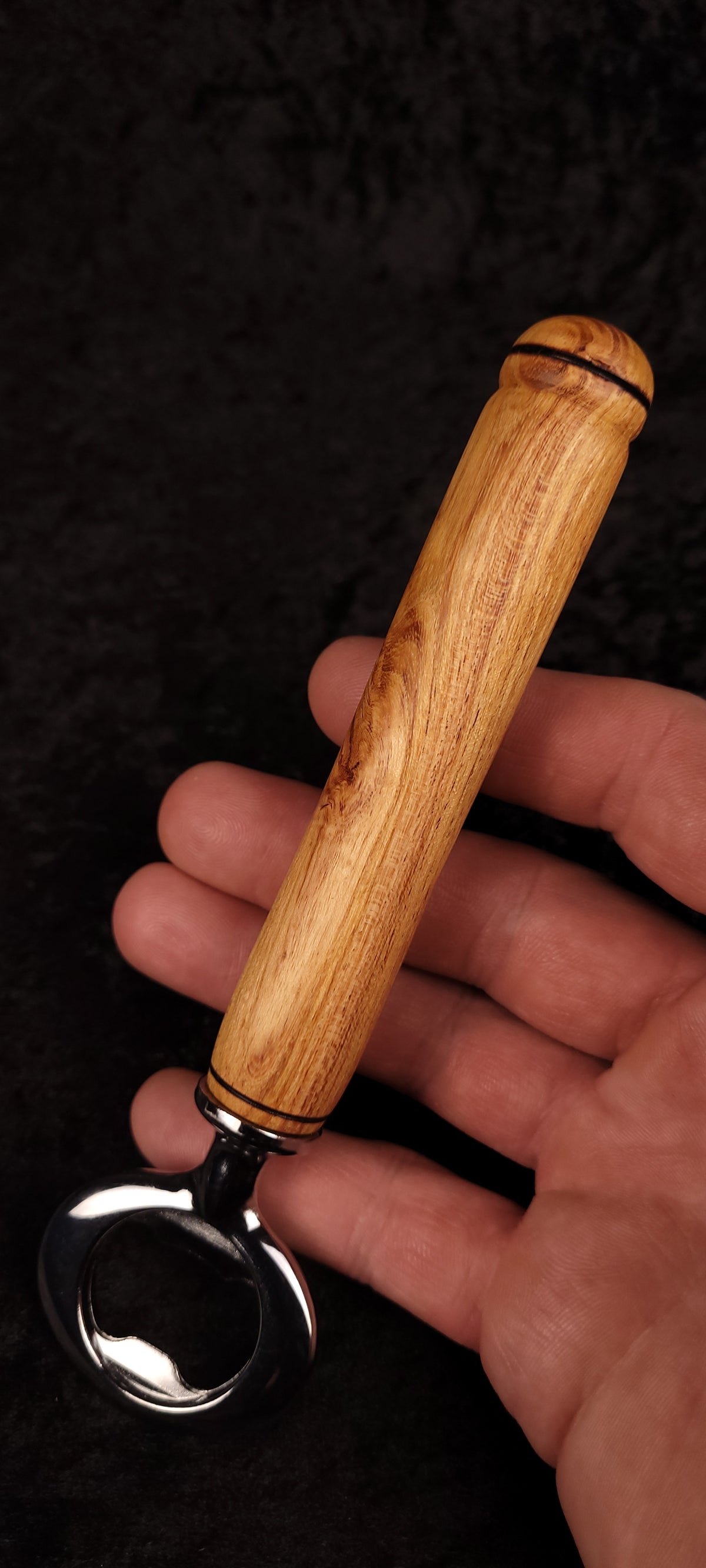 Locust wood bottle opener held in hand, showing opener head