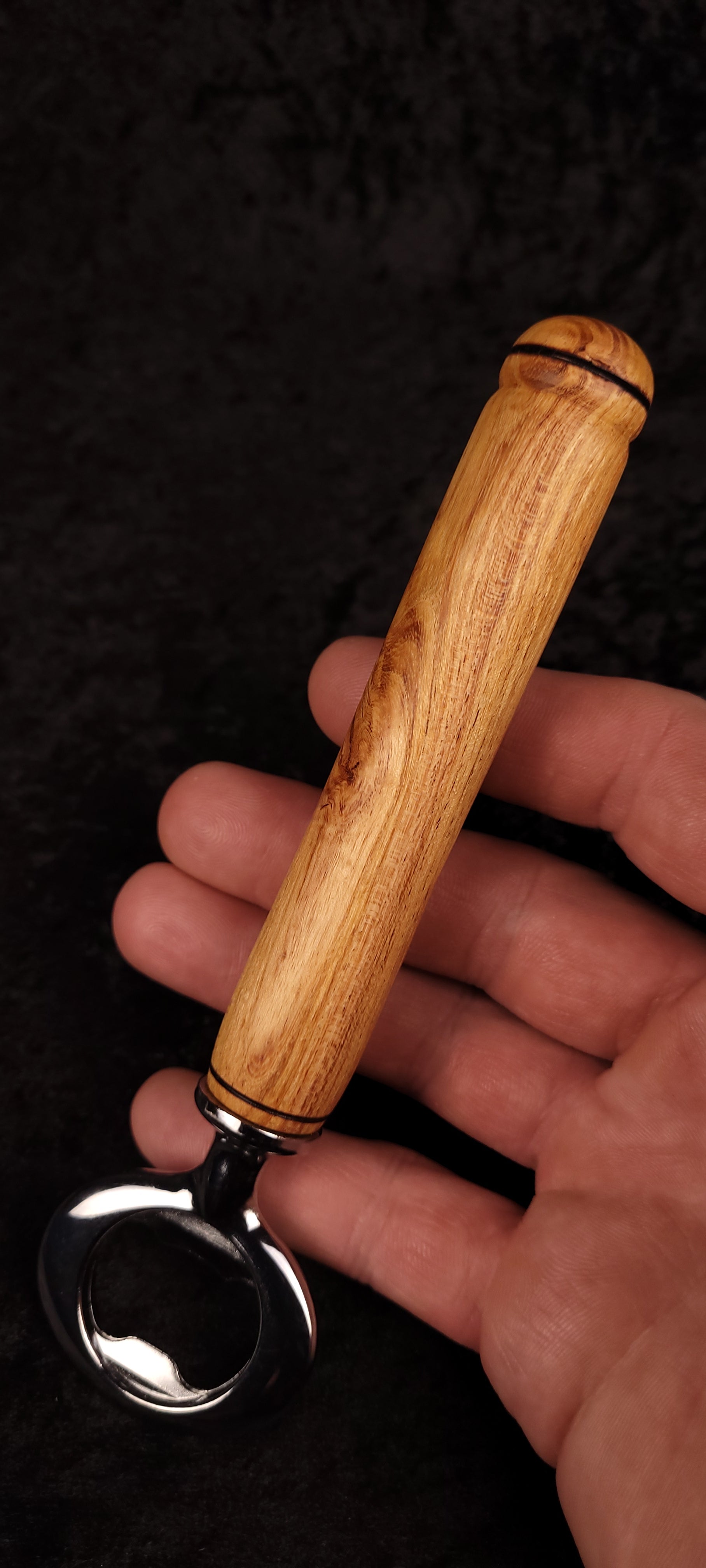 Locust wood bottle opener held in hand, showing opener head