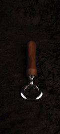 Walnut wood bottle opener on dark background, top view