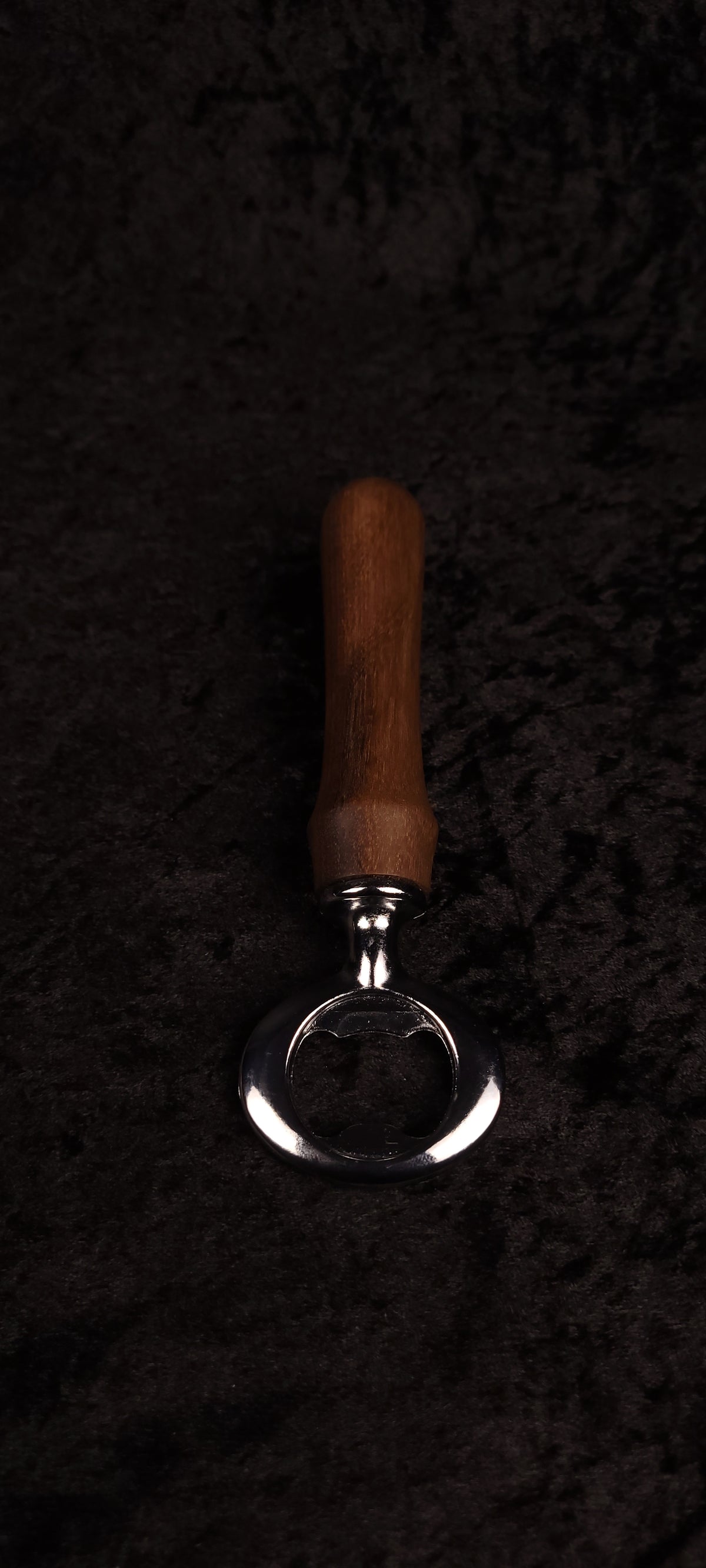 Walnut wood bottle opener on dark background, top view