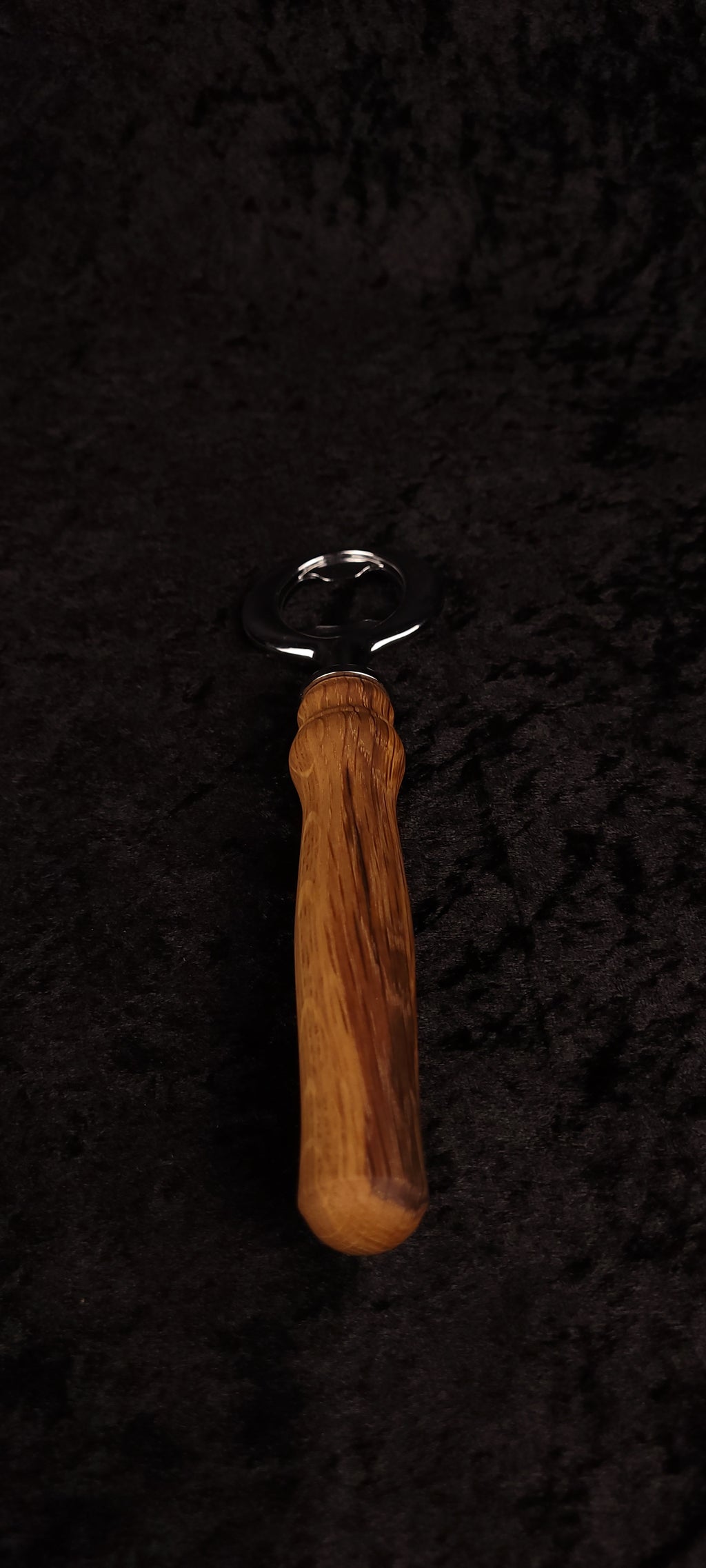 Oak wood bottle opener on dark background, top view