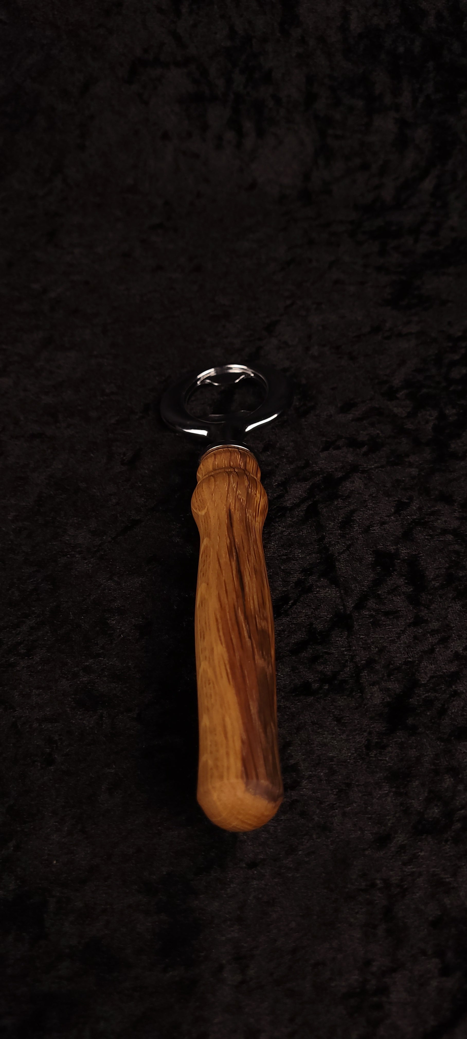 Oak wood bottle opener on dark background, top view